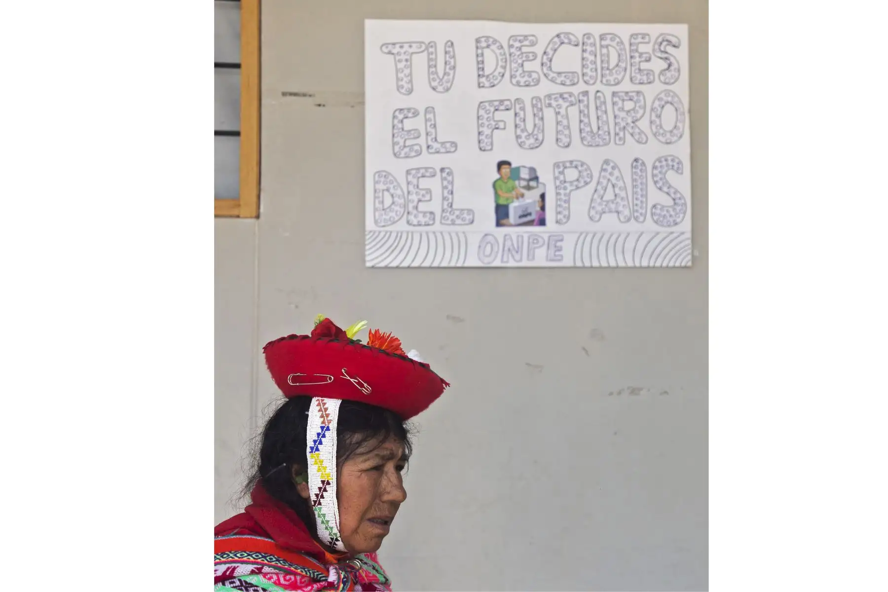 Una mujer indígena pasa junto a un letrero que dice "Tú decides el futuro del país" en un colegio electoral durante las elecciones legislativas en Ollantaytambo, en la región Cusco.
Foto: AFP