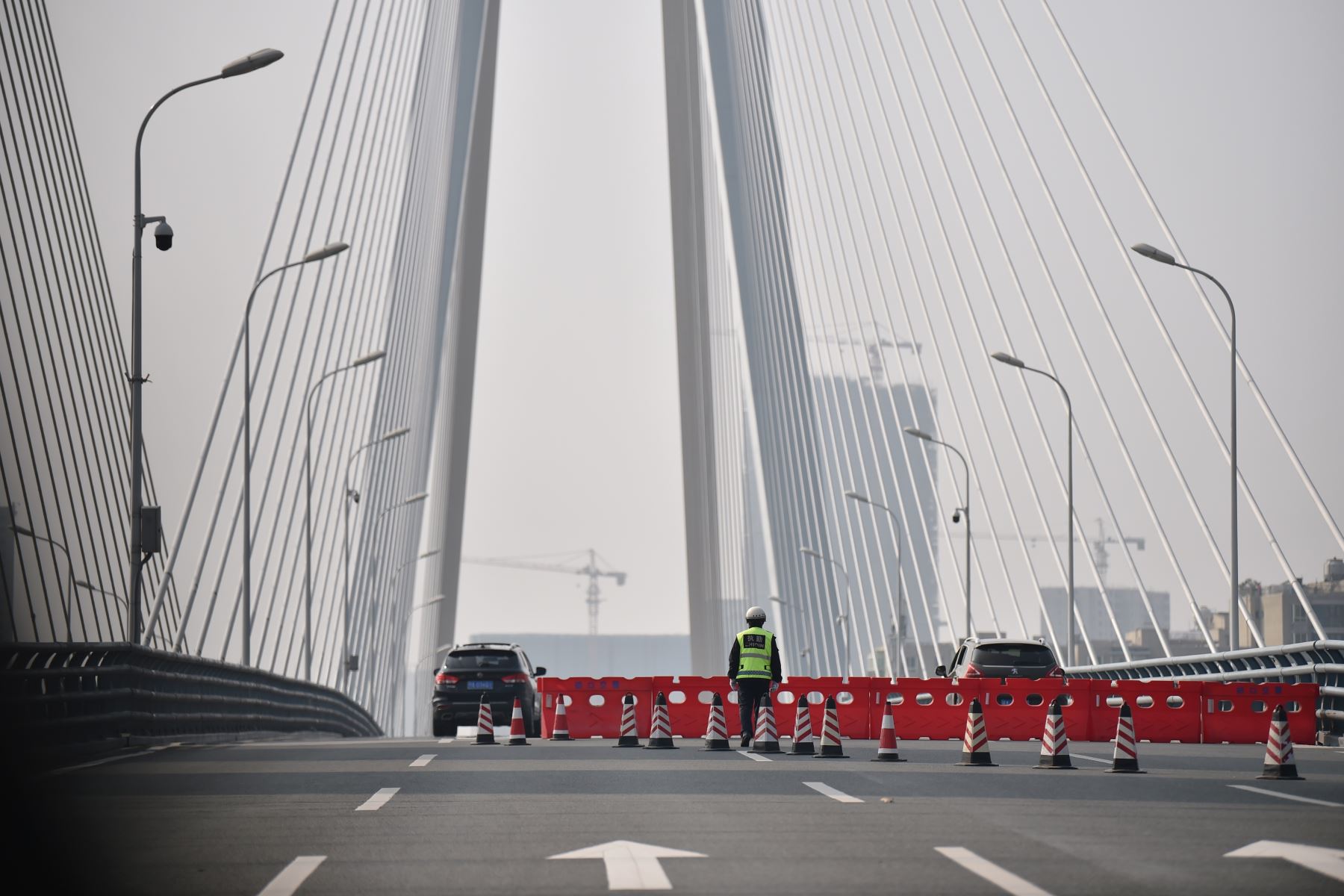 Un policía maneja a un punto de control que bloquea el acceso a través de un puente mientras las personas se quedan en casa y evitan el transporte debido al brote de virus en la ciudad de Wuhan en la provincia de Hubei. Foto: AFP