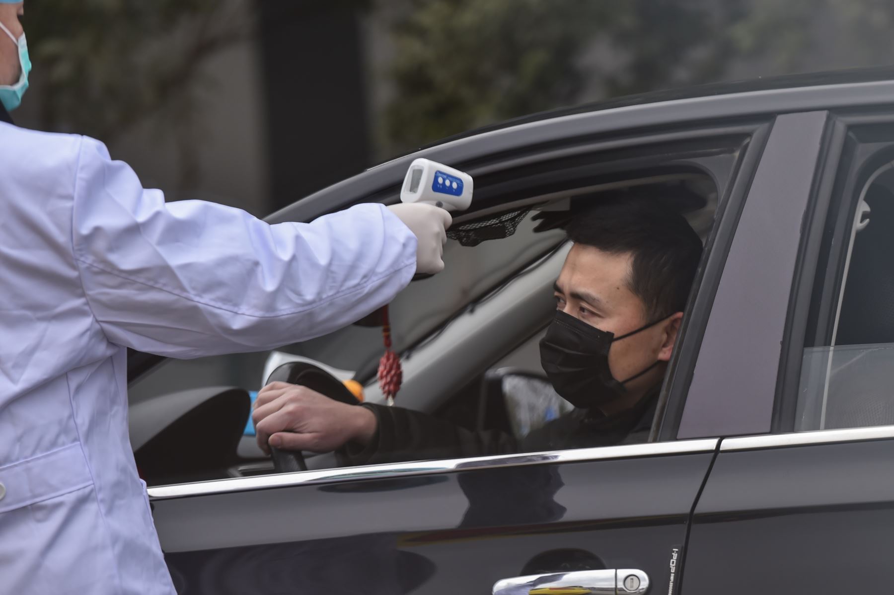 Una policía toma la temperatura de un conductor en un puesto de control en una calle en las afueras de Wuhan, China en medio de un brote de virus mortal que comenzó en la ciudad. AFP