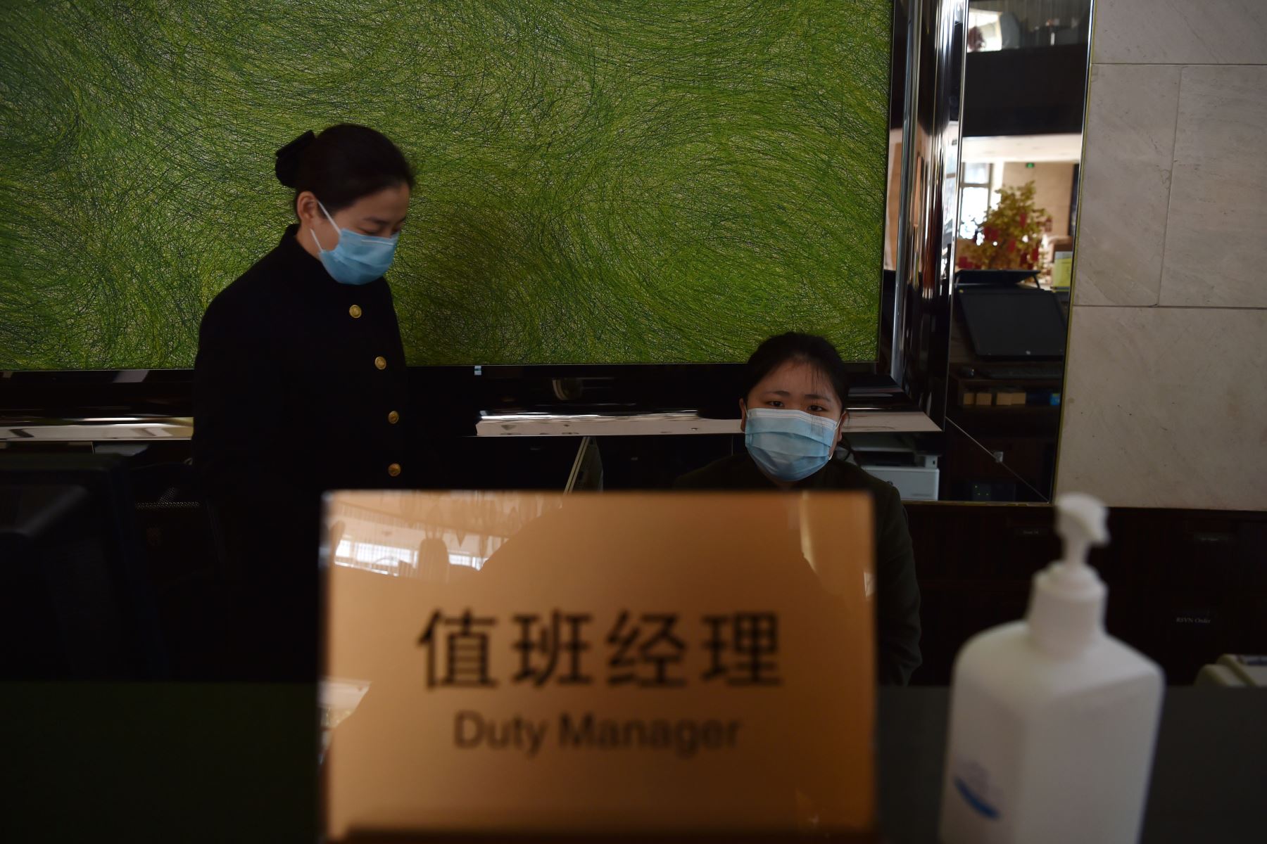 Personal de hotel usan máscaras faciales para ayudar a protegerse contra la propagación del virus similar al SARS que afecta a la ciudad  de Wuhan. AFP