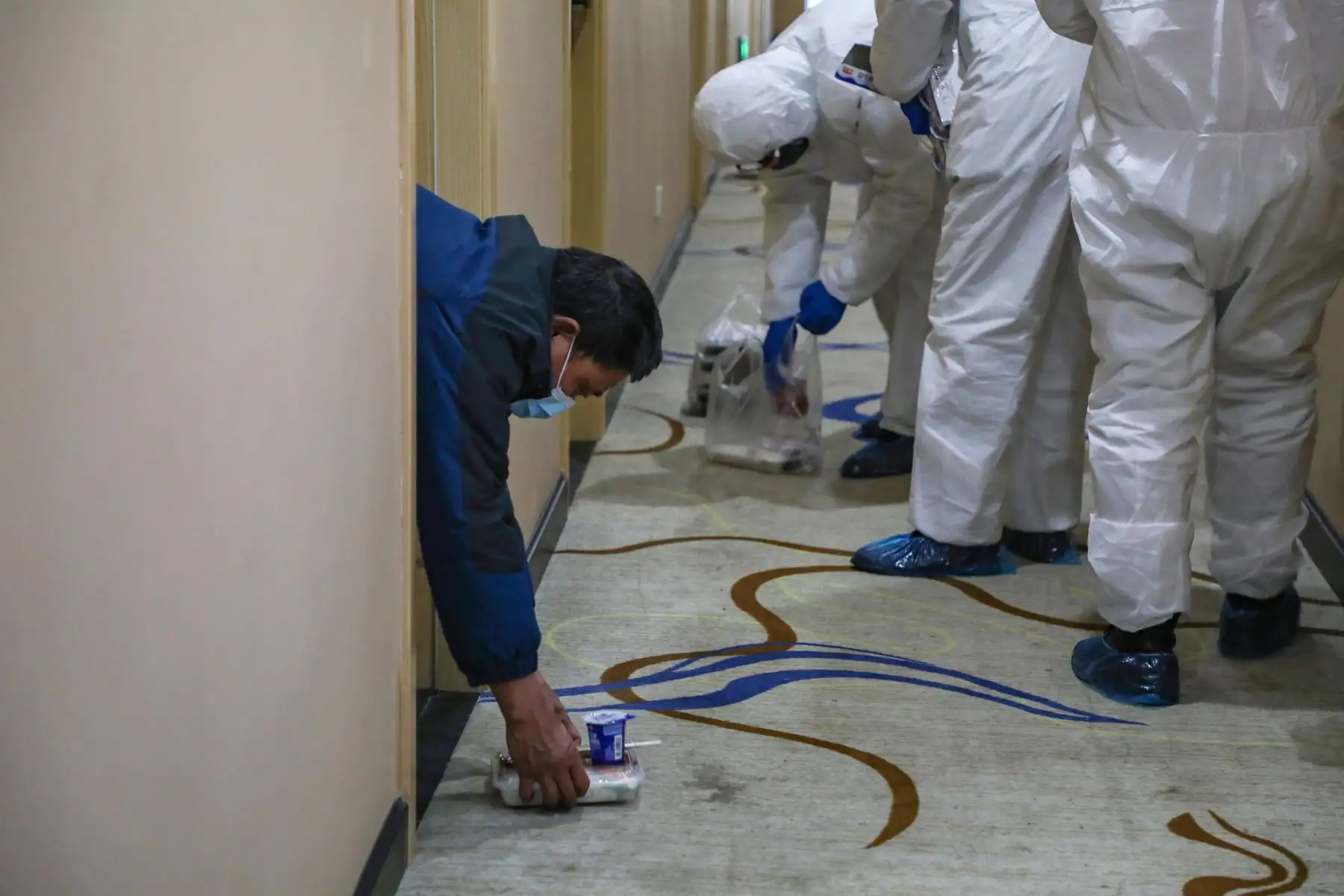 Miembros del personal médico que dejan las loncheras en el suelo para que los pacientes eviten la infección cruzada en una zona de cuarentena en Wuhan. Foto: AFP