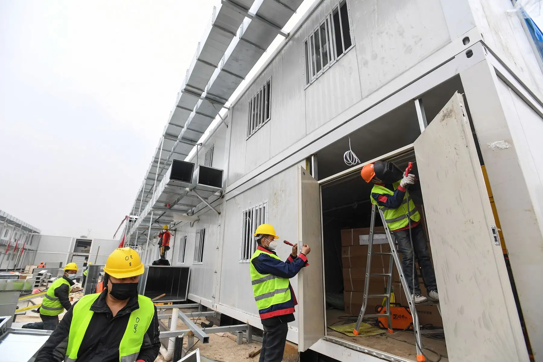 Empleados chinos trabajan en la construcción del hospital Huoshenshan, que significa "Fire God Mountain", antes de ser entregados al ejército de China en Wuhan. El ejército de China el 2 de febrero recibió el control de un hospital de campo casi terminado que tratará a pacientes en el epicentro de una epidemia de virus mortal que ha tensado severamente las instalaciones médicas. AFP