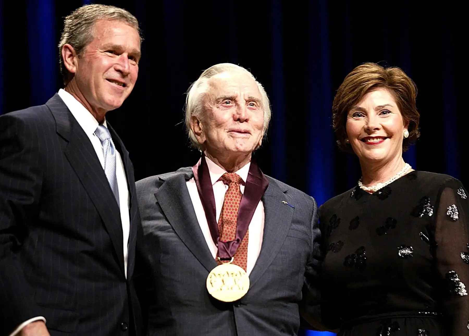 En esta foto de archivo tomada el 22 de abril de 2002, el presidente estadounidense George W. Bush (izq.) Y la primera dama Laura Bush (d) felicitan al actor Kirk Douglas en el Salón de la Constitución del DAR en Washington.
Foto: AFP