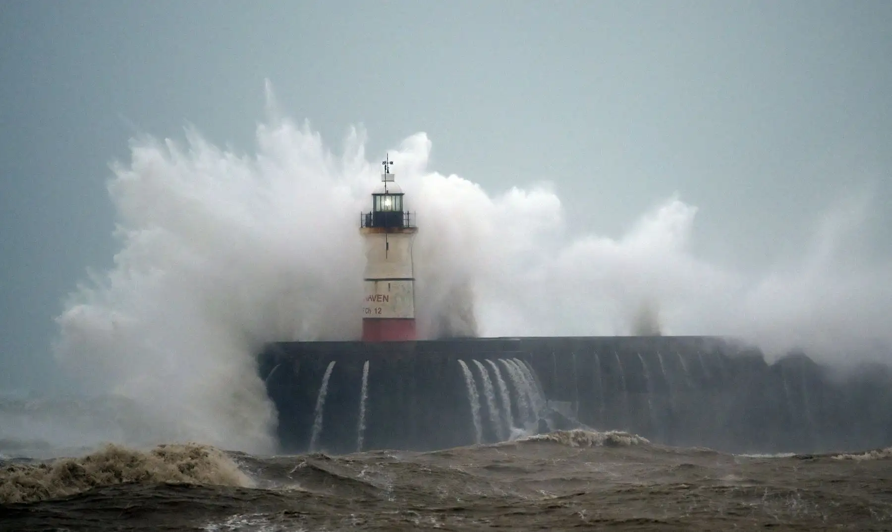 Las olas rompen sobre el faro de Newhaven en la costa sur de Inglaterra. Foto: AFP