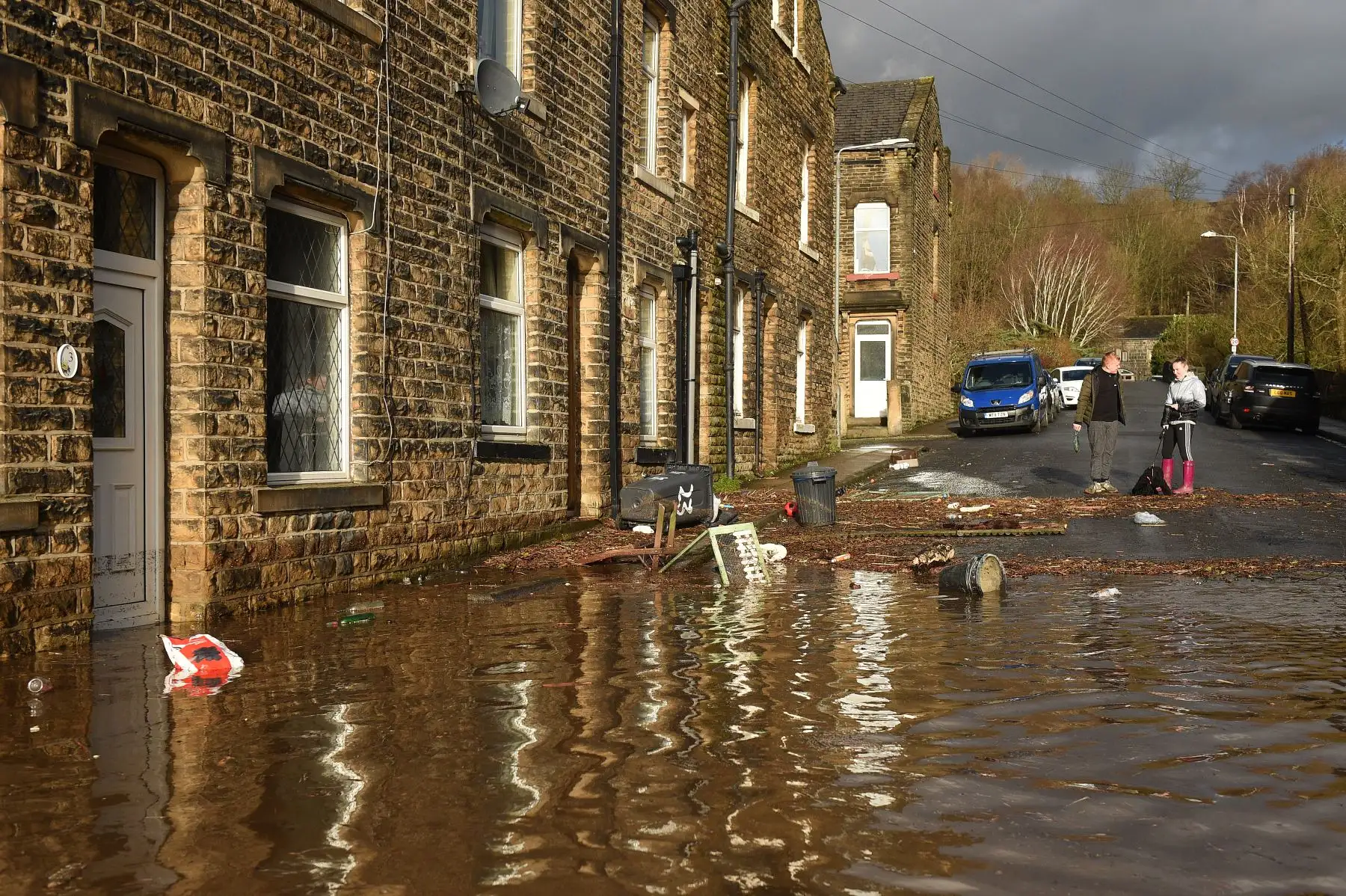 La gente se para cerca de los escombros causados ​​por las inundaciones en una calle de Mytholmroyd, en el norte de Inglaterra.
Foto: AFP