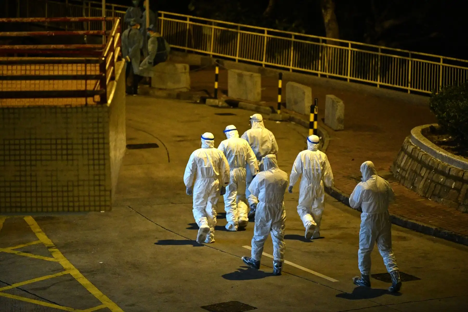 El personal médico que usa trajes protectores camina por los terrenos de una propiedad residencial en Hong Kong, tras confirmase que dos personas habían contraído el coronavirus. AFP