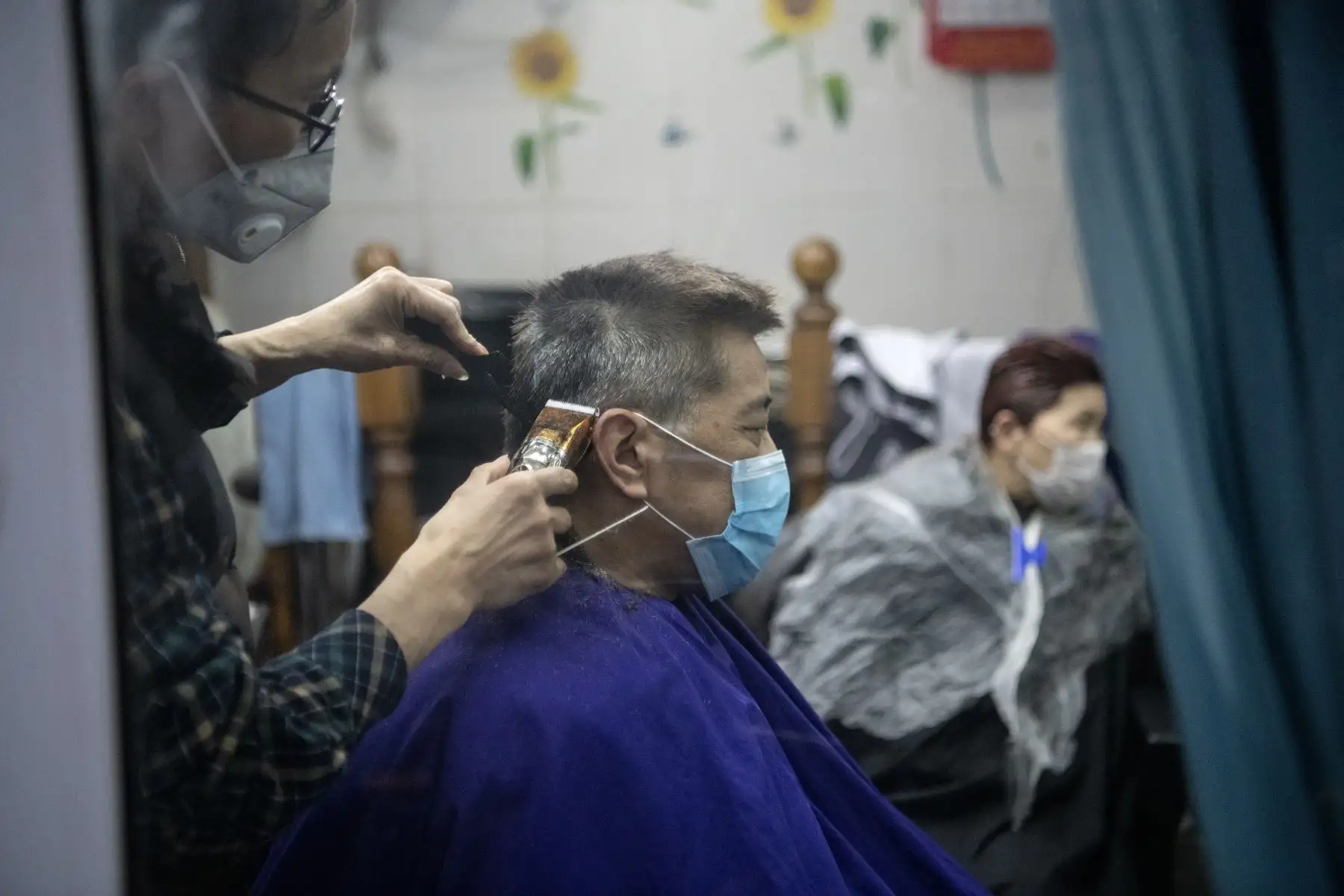 Un hombre con una máscara protectora se corta el cabello por un barbero en Shanghai . AFP