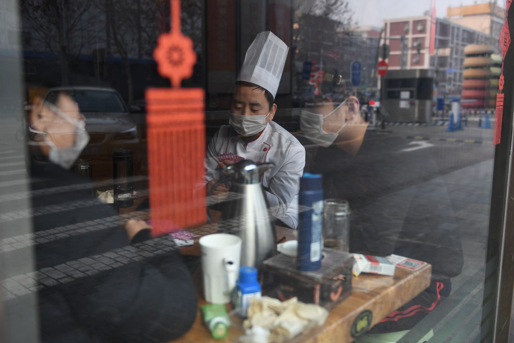 Los trabajadores del restaurante juegan a las cartas en la ventana de su restaurante en Beijing. AFP