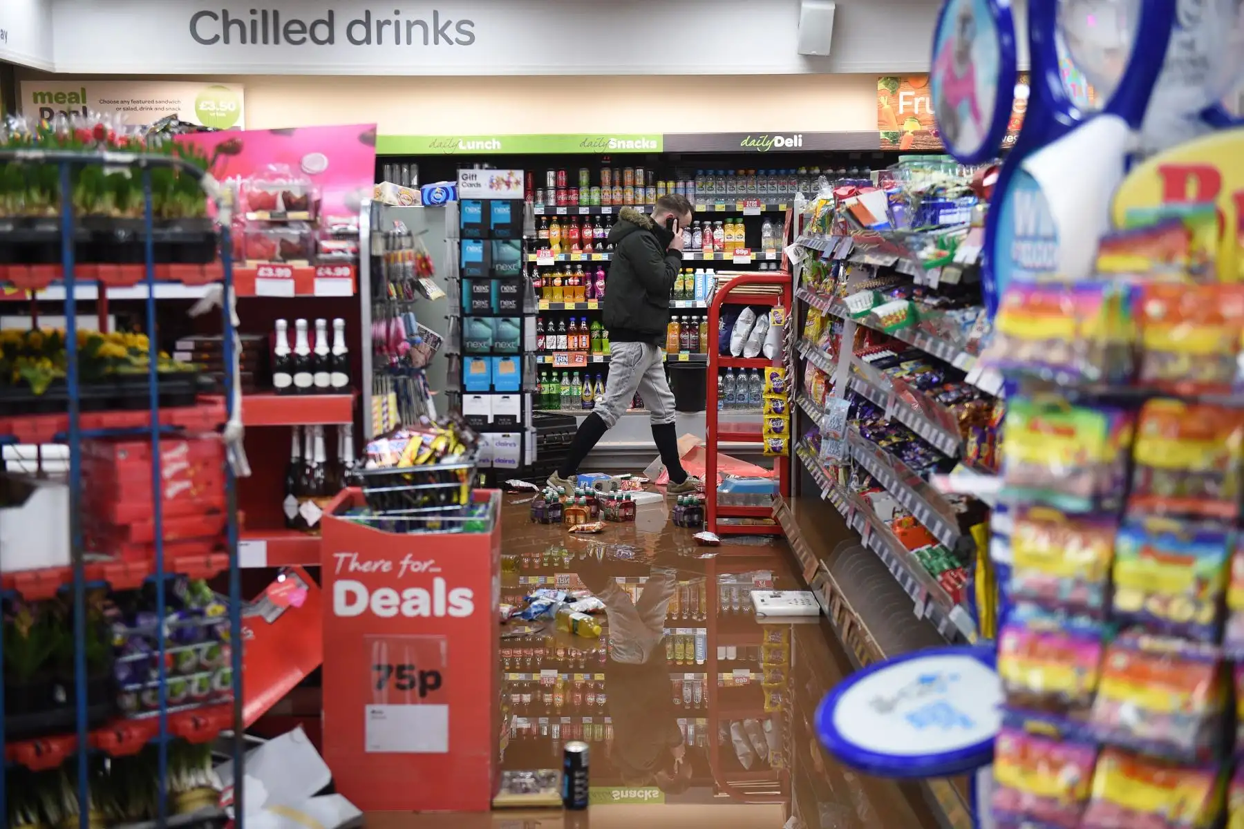Un hombre camina por una tienda inundada en Tenbury Wells, en el oeste de Inglaterra. Foto: AFP