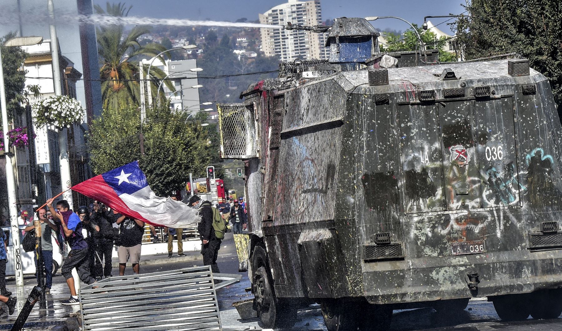 Un manifestante con una bandera chilena huye de un cañón de agua de la policía durante una protesta contra el gobierno del presidente chileno, Sebastián Piñera, en Viña del Mar. AFP