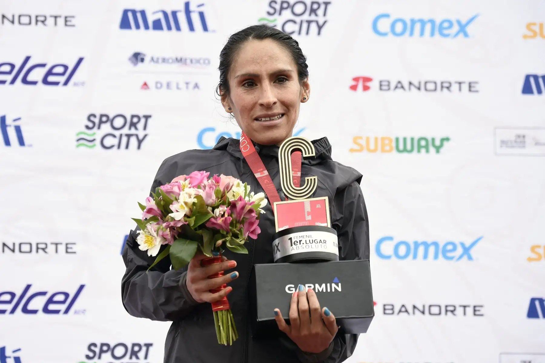 Gladys Tejeda celebra con su trofeo después de ganar el Maratón Internacional de la Ciudad de México, en el estadio Olímpico Universitario el 27 de agosto de 2017. Foto: AFP