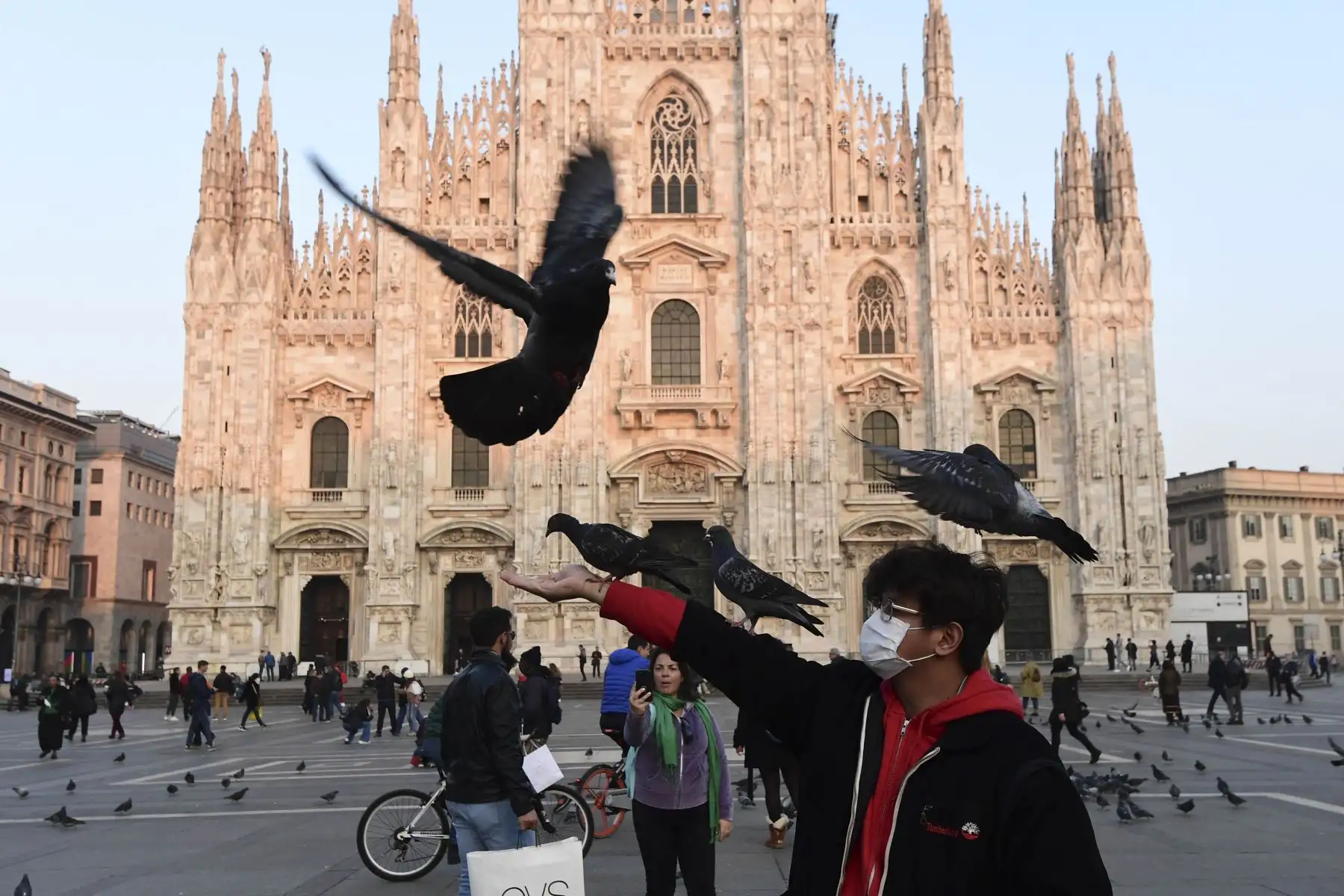 Un hombre con una máscara protectora juega con palomas en la Piazza del Duomo, en el centro de Milán, el 24 de febrero de 2020 tras las medidas de seguridad tomadas en el norte de Italia contra el COVID-19, el nuevo coronavirus. Foto: AFP