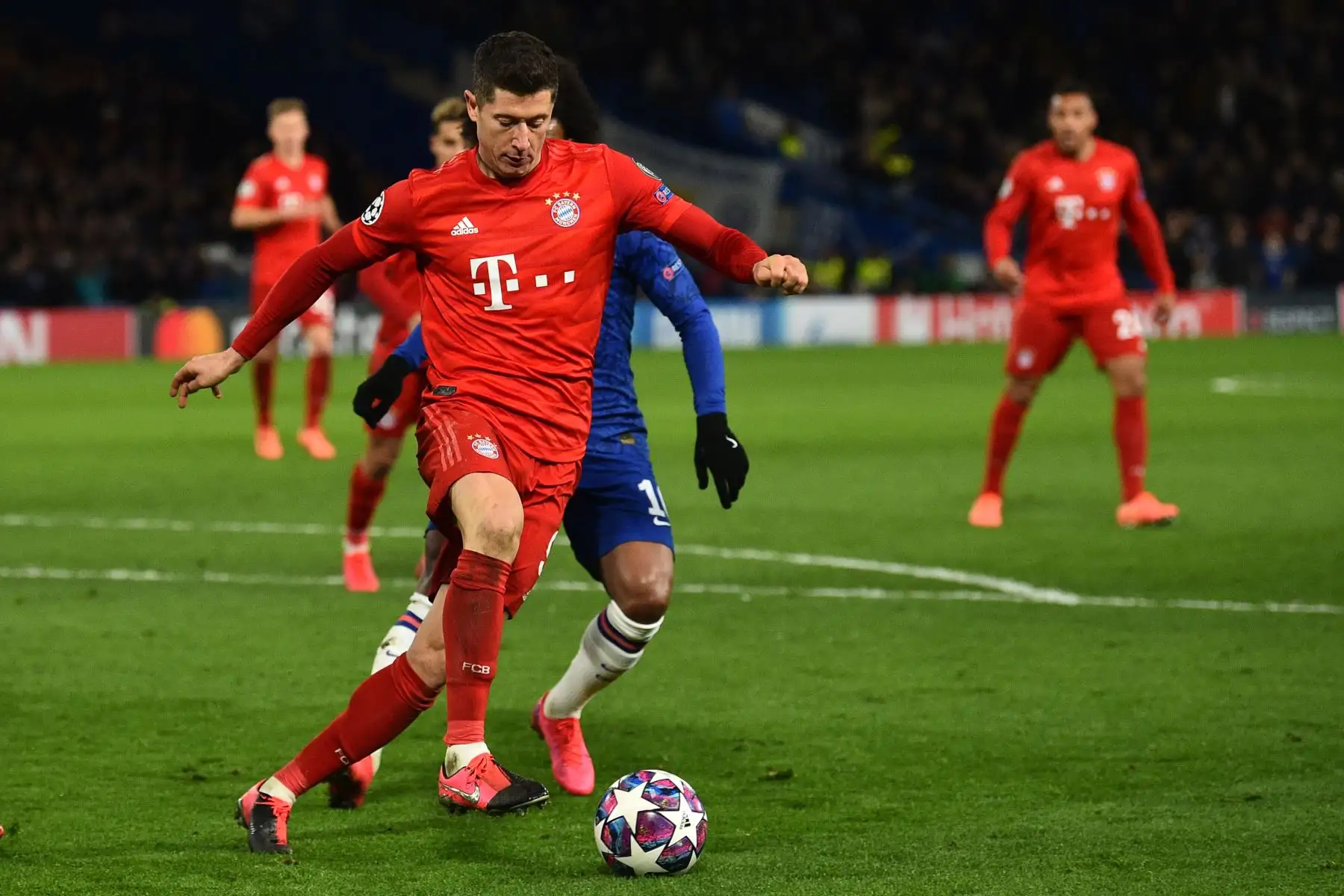 El delantero polaco del Bayern Múnich Robert Lewandowski compite con el centrocampista brasileño del Chelsea Willian durante el partido de ida de octavos de final de la UEFA Champion