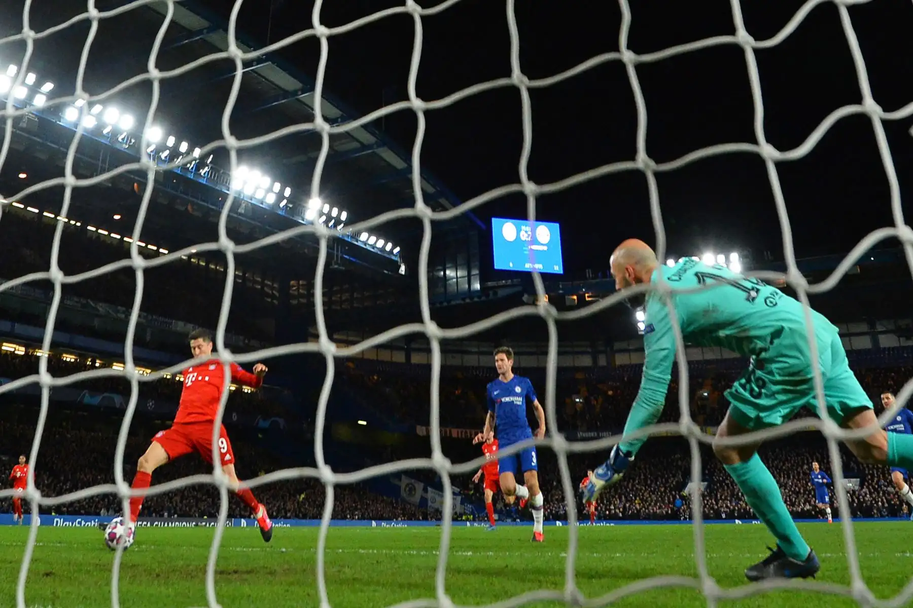 El delantero polaco del Bayern Múnich Robert Lewandowski (L) marca su tercer gol al arquero argentino del Chelsea Willy Caballero (R) durante el partido de fútbol de ida de octavos de final de la UEFA Champion