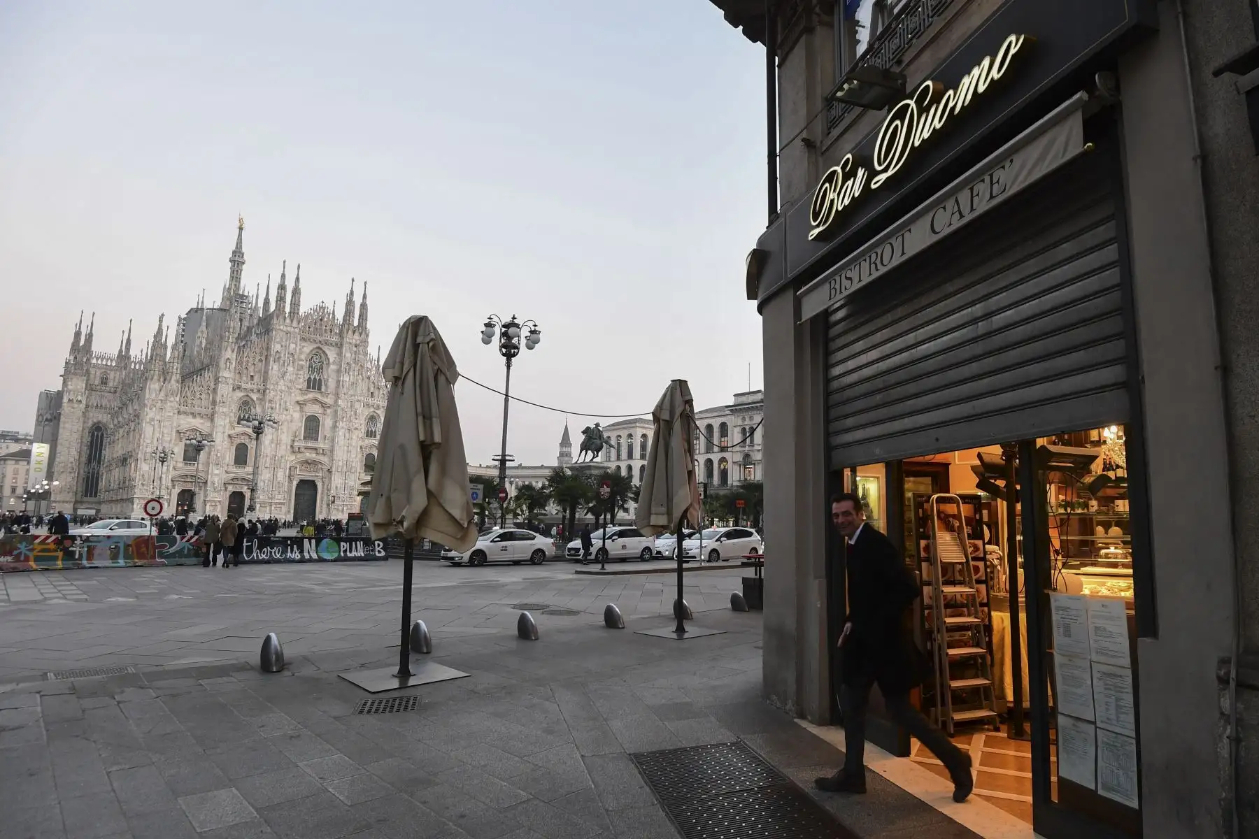 Un hombre sale de un bar al lado de la Piazza del Duomo en el centro de Milán que cierra a las 6 p.m.  luego de tomar medidas de seguridad en el norte de Italia contra el COVID-19. AFP