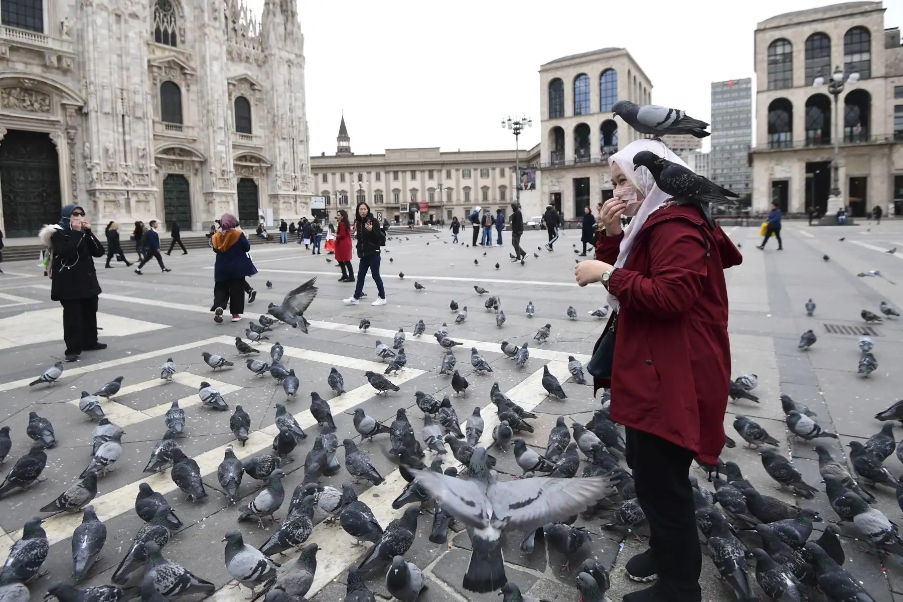 Un turista con una máscara protectora rodeada de pájaros se encuentra en la Piazza del Duomo, en el centro de Milán.
Foto: AFP