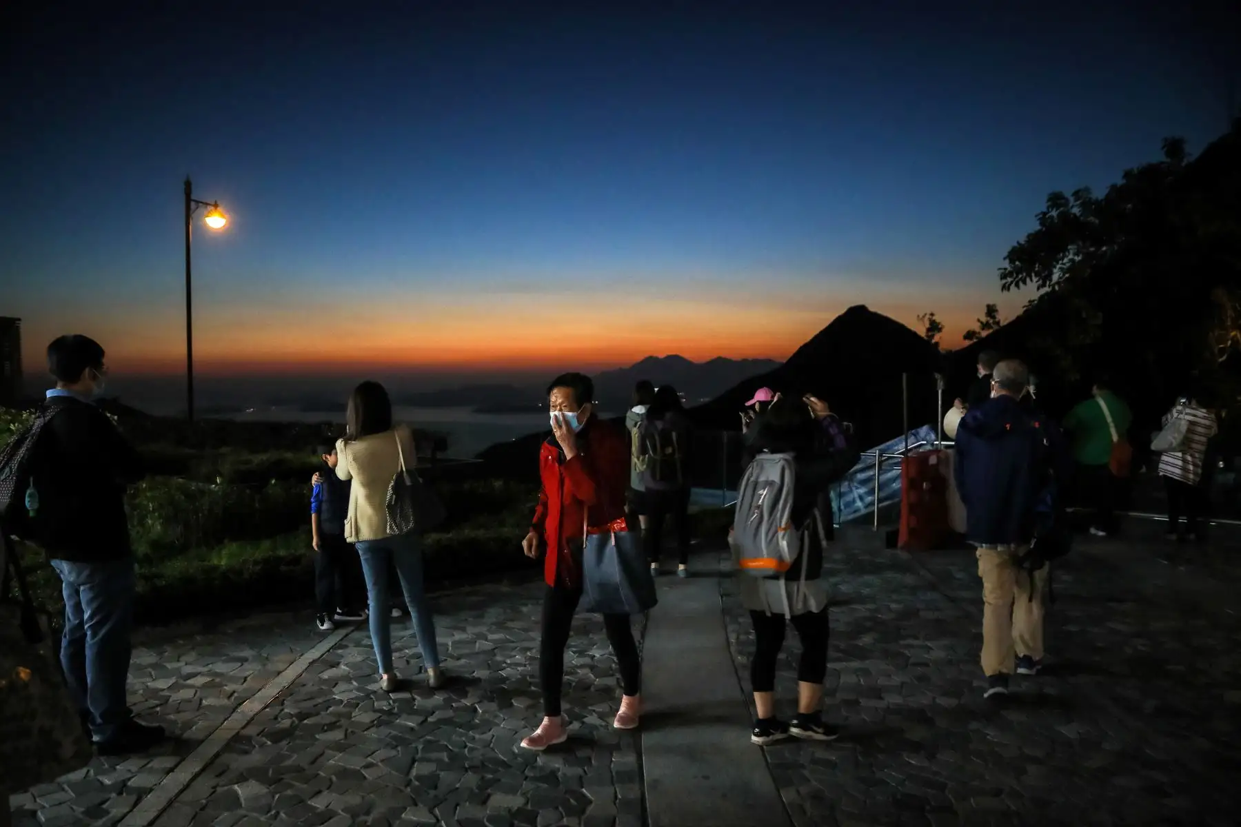 Las personas que usan mascarillas como medida de precaución contra la propagación del nuevo coronavirus Covid-19, contemplan la puesta de sol en Hong Kong.
Foto: AFP