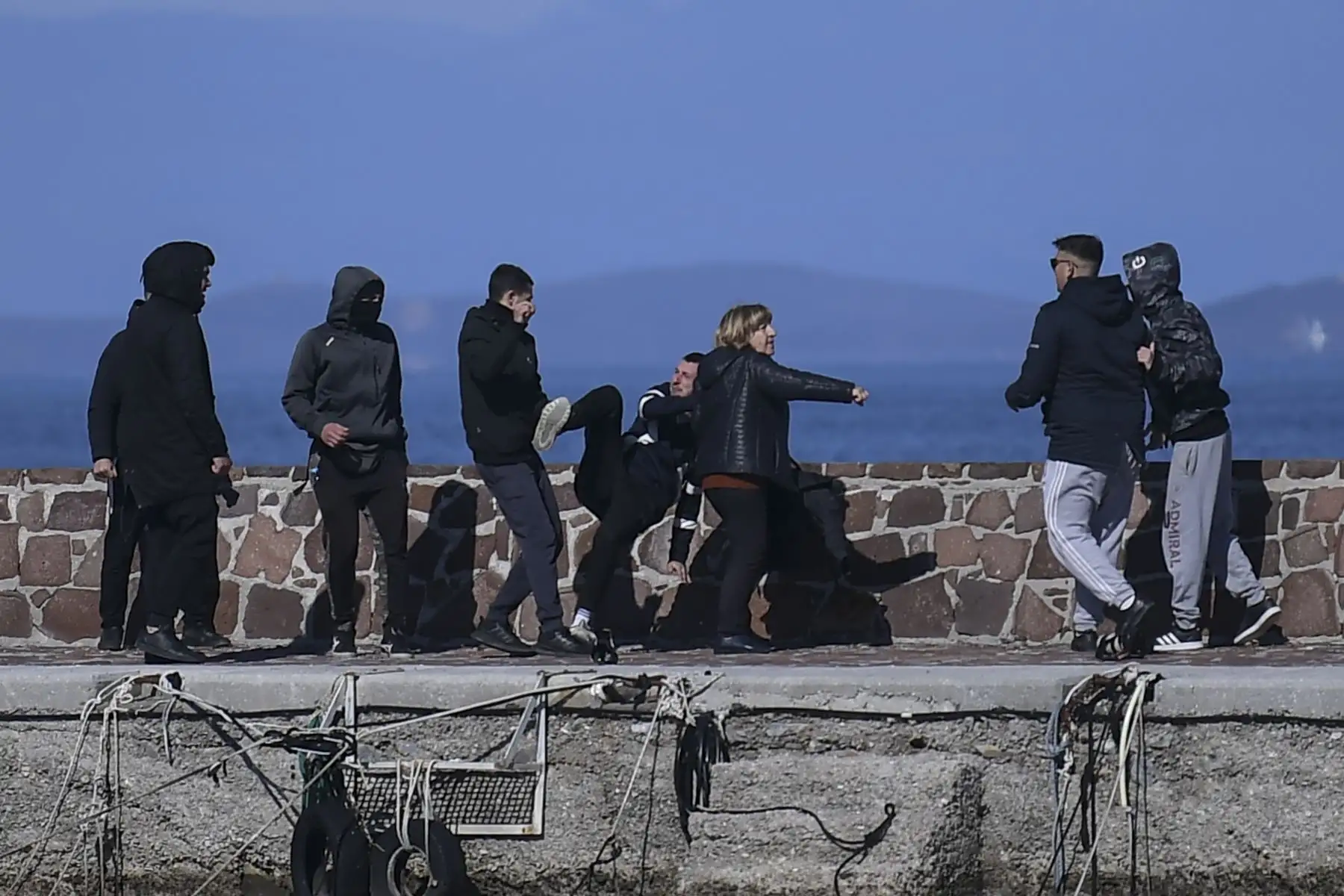 Un periodista recibe ayuda de una mujer mientras es atacado por residentes que intentan evitar que los migrantes desembarquen en la isla griega de Lesbos. Foto: AFP