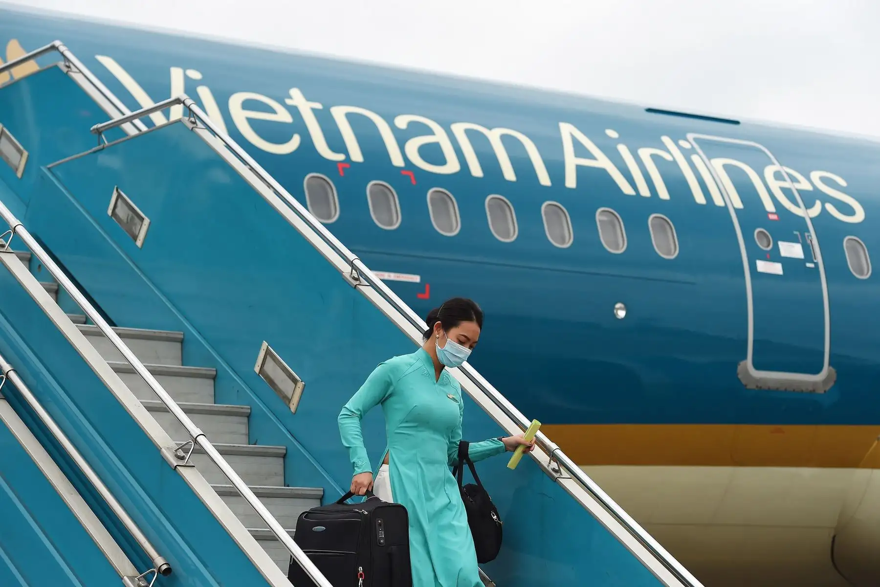 Un miembro de la tripulación de vuelo de Vietnam Airlines con máscara facial en medio de la preocupación por la propagación del coronavirus COVID-19 desembarca de un vuelo que regresa de Taiwán en el Aeropuerto Internacional Noi Bai en Hanoi. Foto: AFP