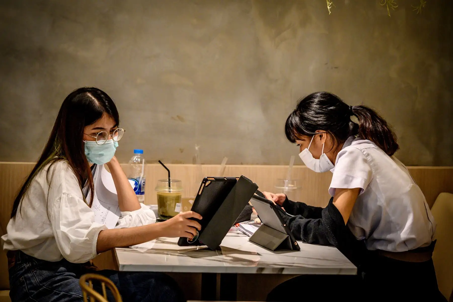Los estudiantes, que usan máscaras faciales en medio del temor a la propagación del nuevo coronavirus COVID-19, trabajan en una cafetería en Bangkok. Foto: AFP