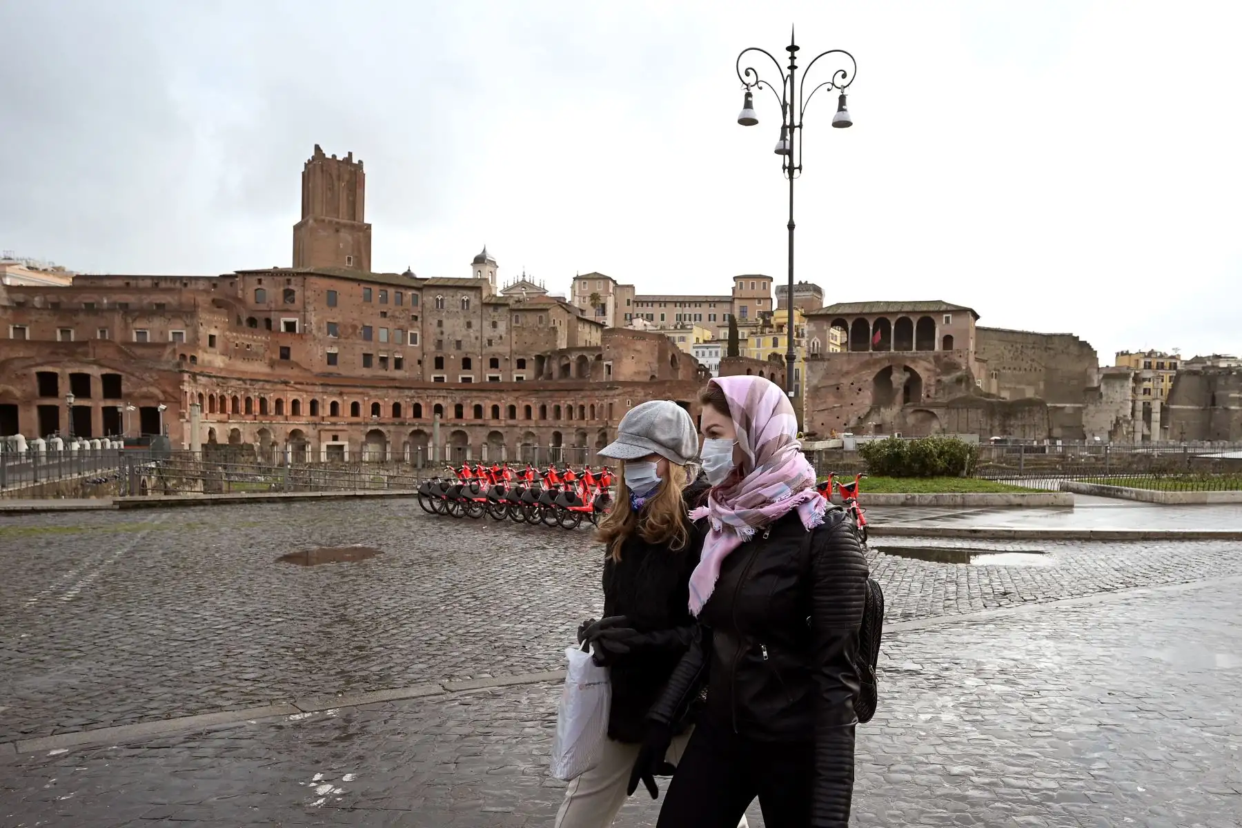 Dos mujeres con máscaras protectoras pasan por el Foro de Trajano en Roma. Foto: AFP