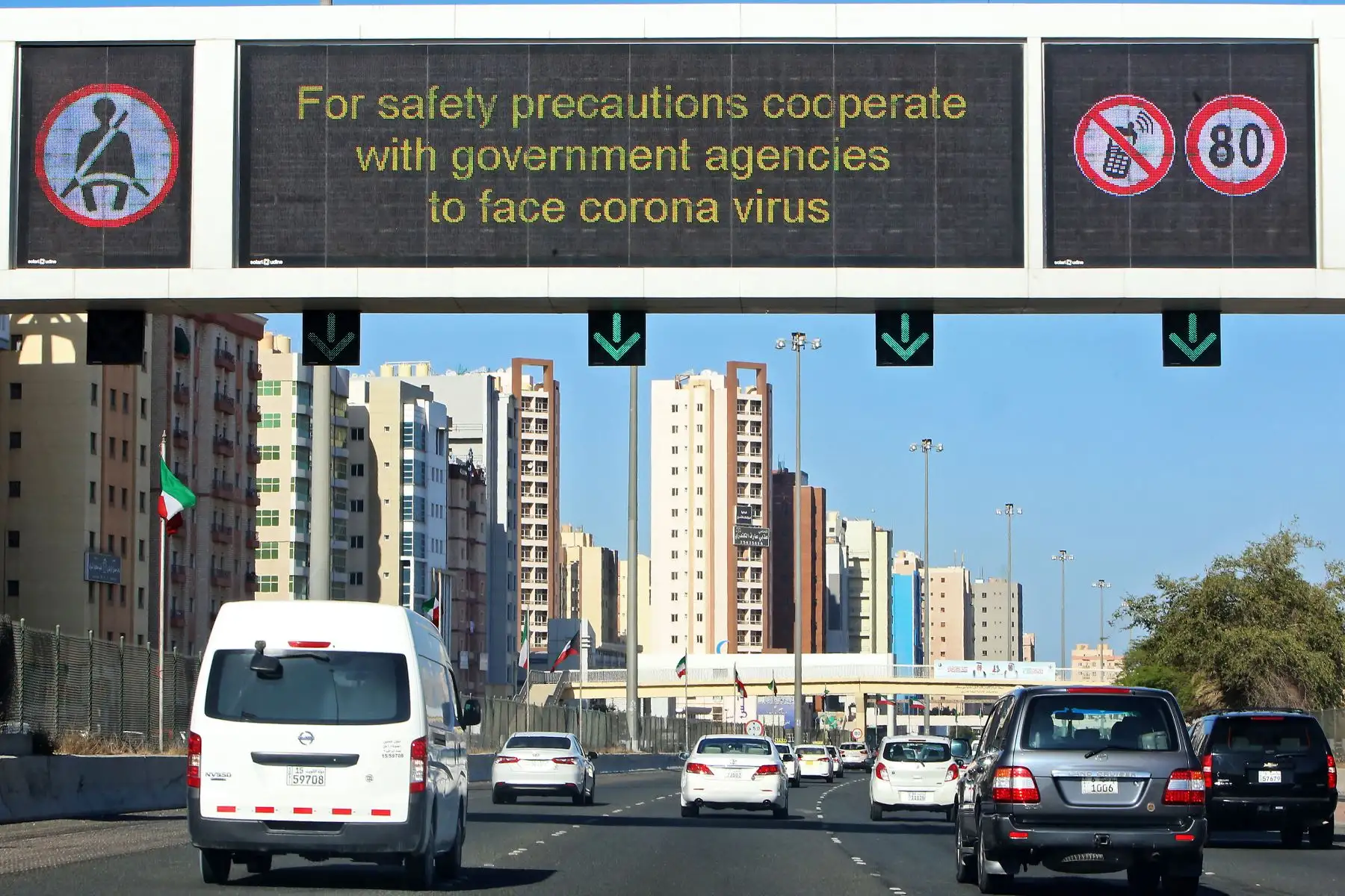 Los vehículos pasan por una valla publicitaria que muestra instrucciones de precaución contra la enfermedad del coronavirus COVID-19 en Kuwait. Foto: AFP