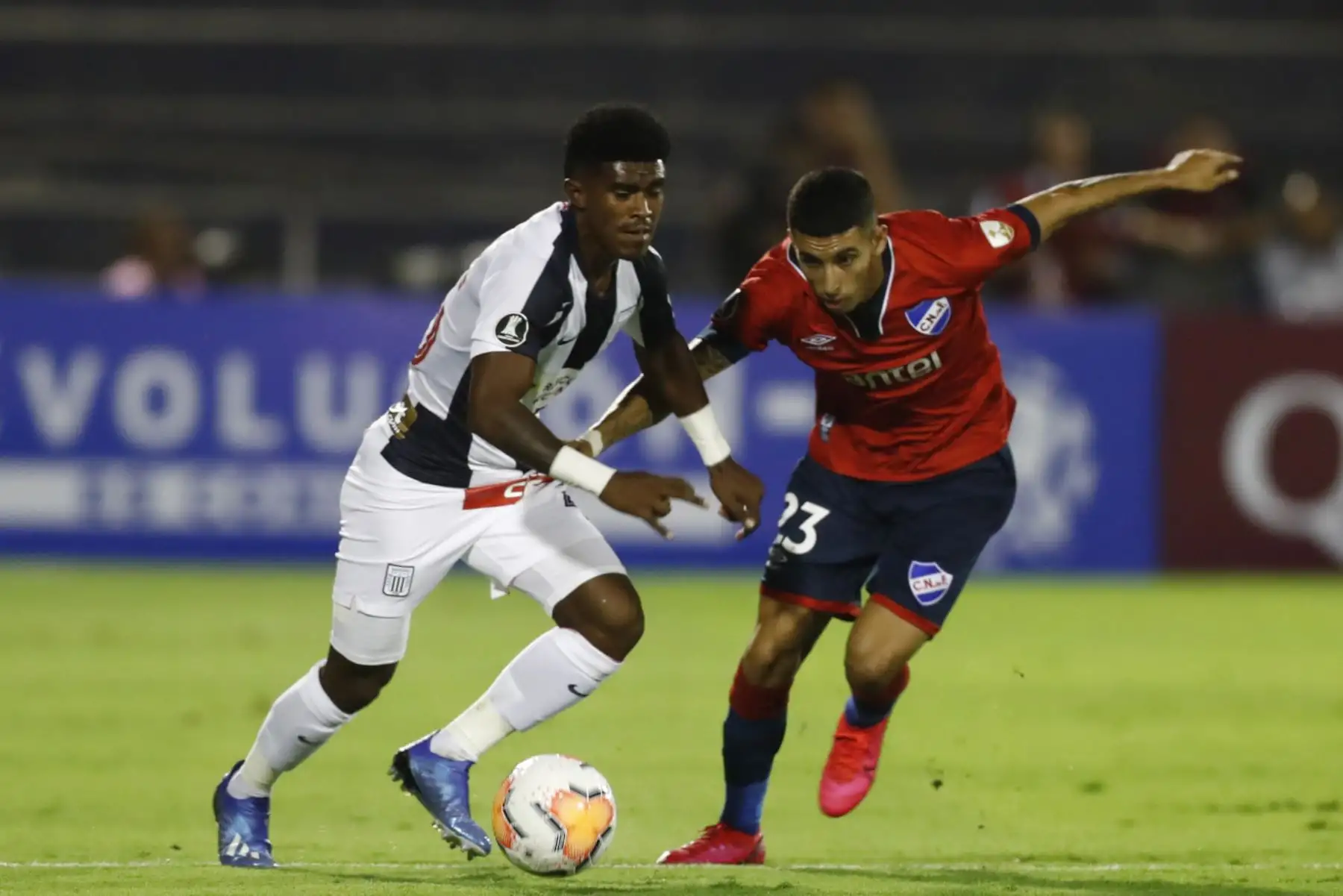 El futbolista del Alianza Lima Oslimg Mora, disputa el balón con el jugador  Santiago Mariano Rodríguez Molina del Nacional de Uruguay, durante el partido por la Copa Libertadores 2020 en el estadio Alejandro Villanueva .Foto:ANDINA/Carlos Lezama