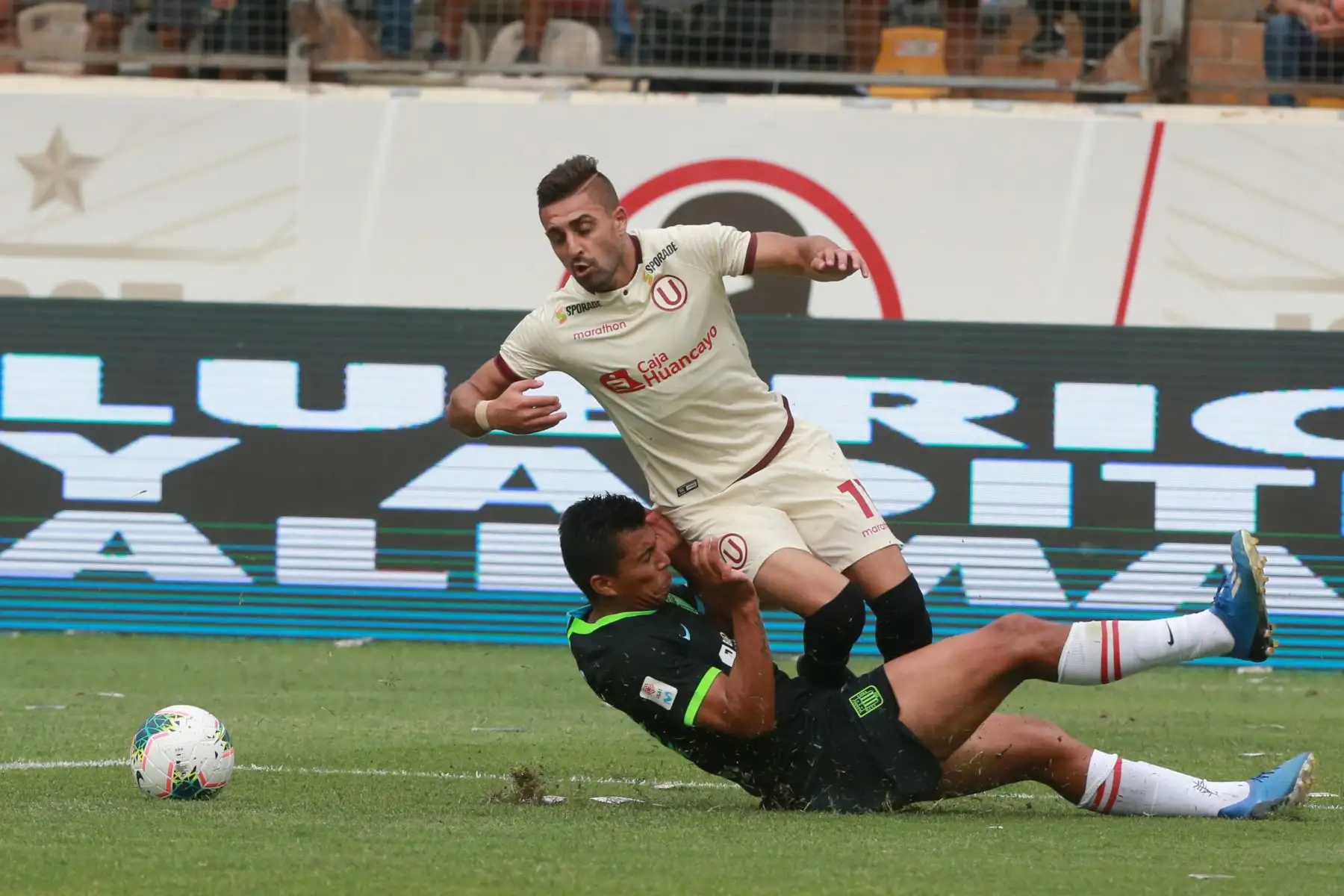 El delantero Luis Urruti de Universitario es derribado por Rinaldo Cruzado,durante el clásico del futbol peruano Liga 1 por el Torneo Apertura en el estadio Monumental.
Foto:ANDINA/Jhony Laurente