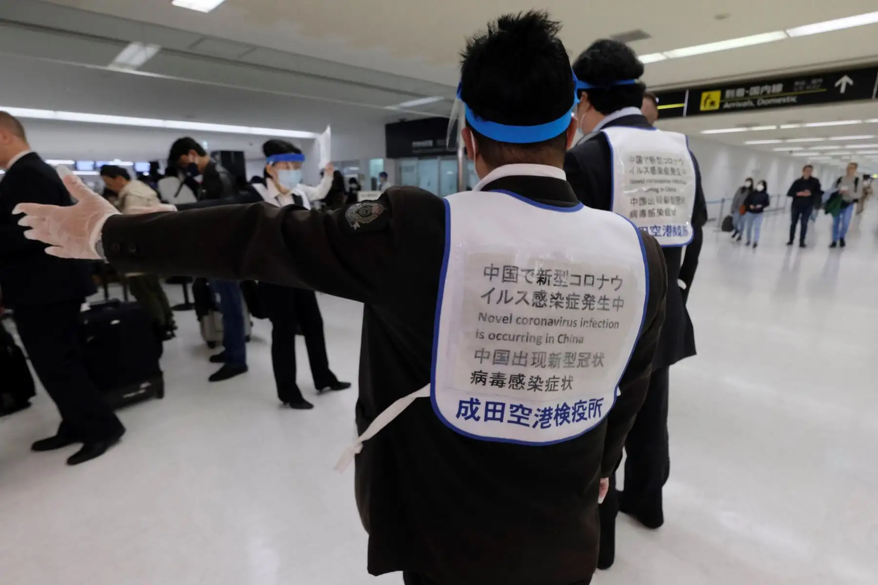 Oficiales ayudan a los pasajeros que llegan desde Hong Kong a una estación de cuarentena en el aeropuerto de Narita en Japón. Foto: AFP