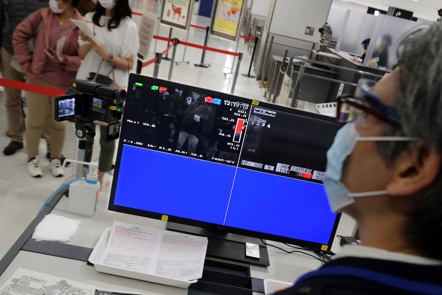 Un oficial con una máscara facial revisa las pantallas que muestran la temperatura corporal de los pasajeros en una estación de cuarentena en el aeropuerto de Narita, prefectura de Chiba en Japón. Foto: AFP