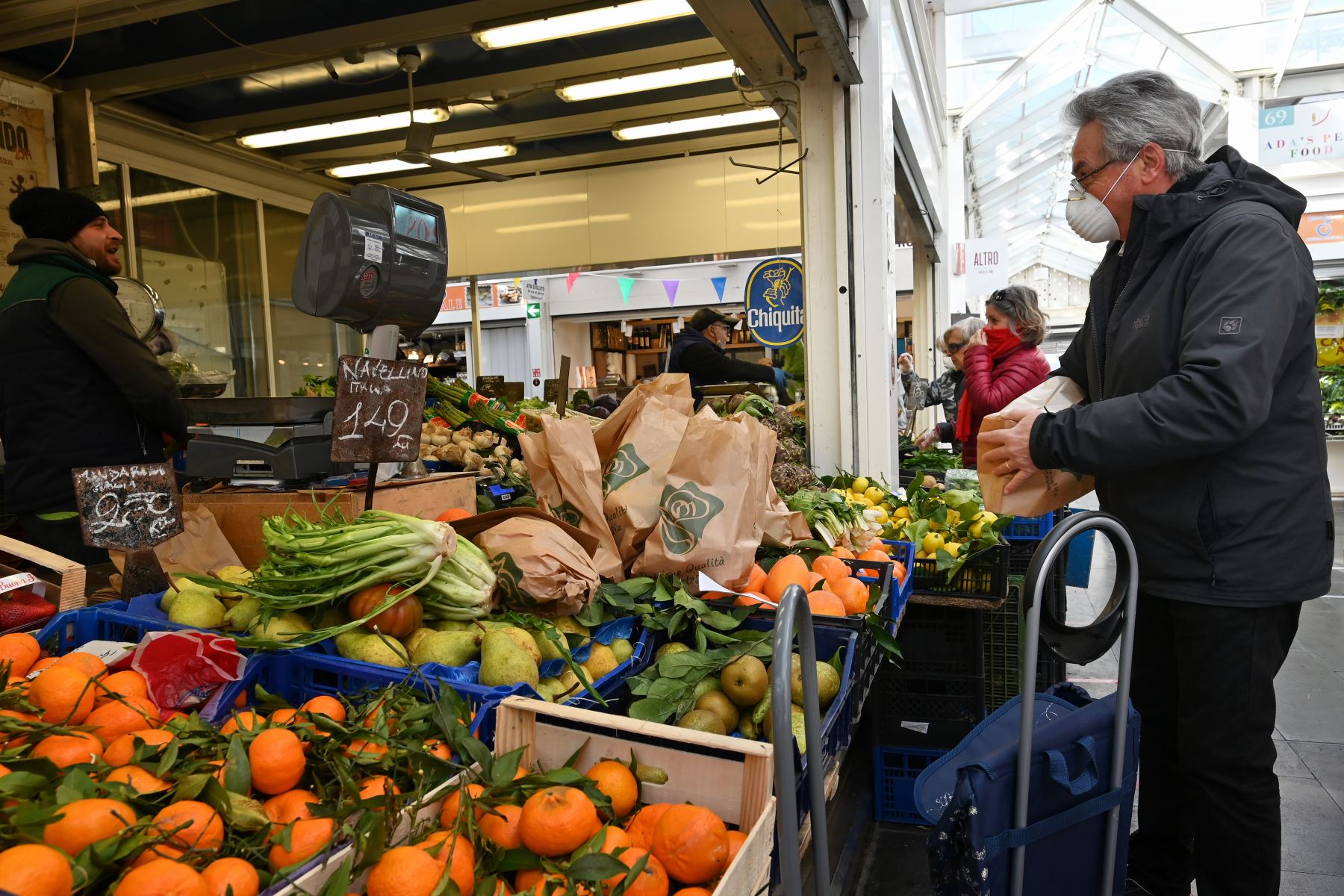 Un hombre que llevaba una máscara respiratoria compra en un mercado de frutas y verduras en Roma. Foto: AFP