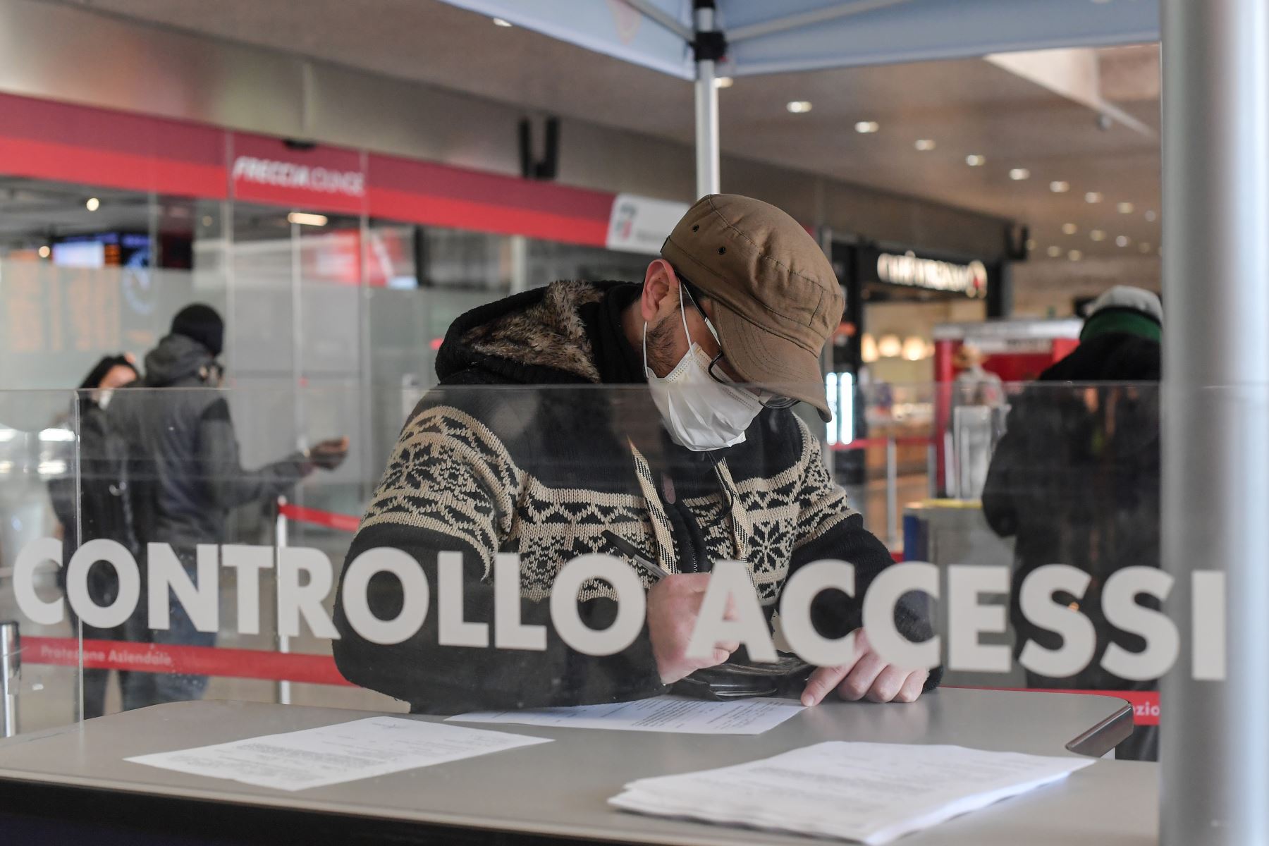 Un hombre con una máscara respiratoria llena un formulario en la estación de trenes Termini en Roma. Foto: AFP