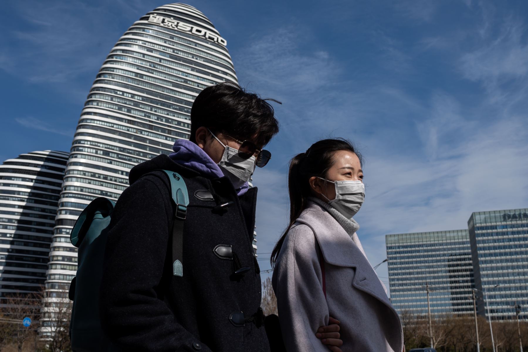 Las personas que usan mascarillas como medida preventiva contra el coronavirus COVID-19 caminan en una calle en Beijing. Foto: AFP