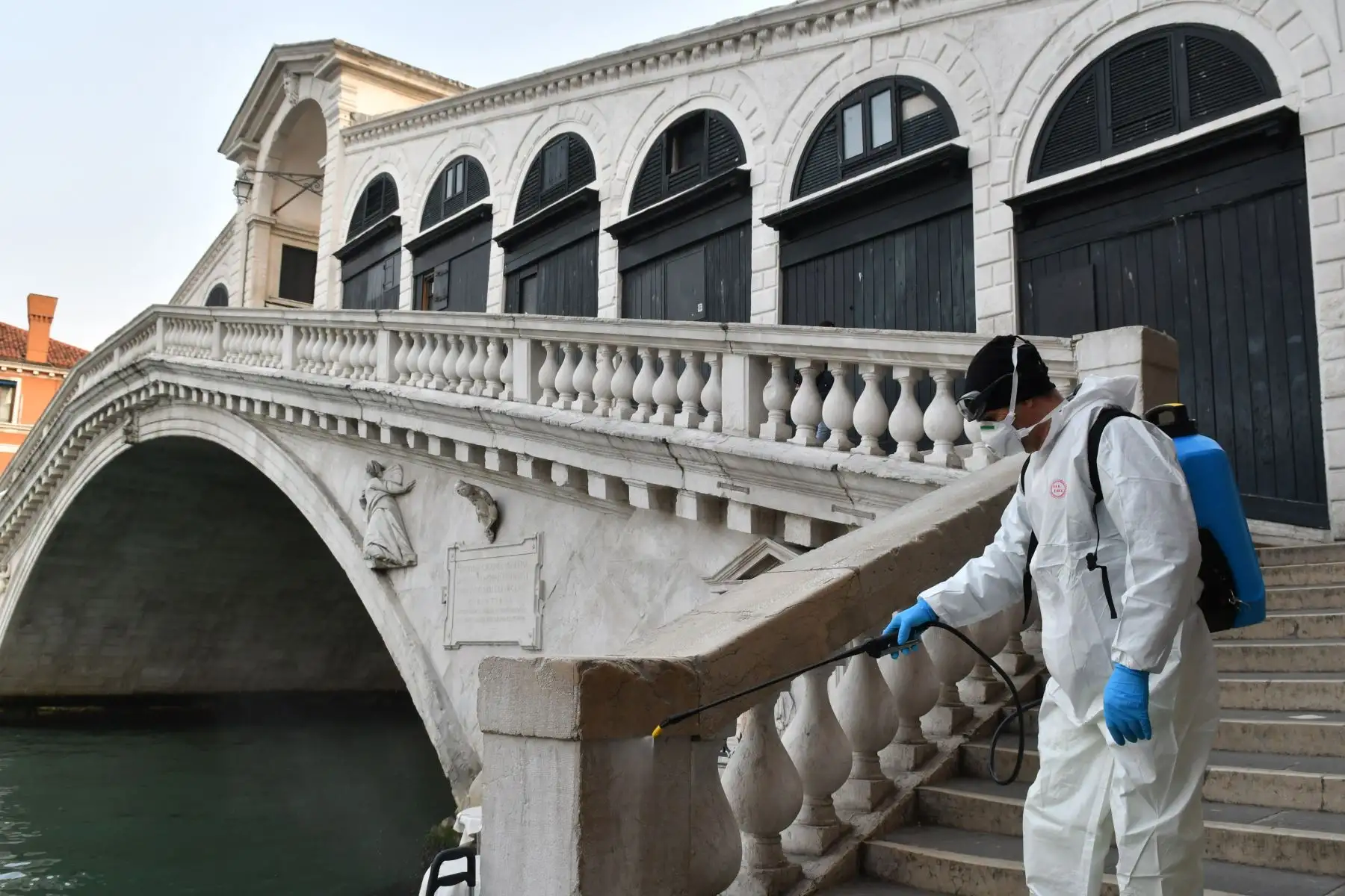 Un empleado de la empresa municipal Veritas rocía desinfectante en áreas públicas en el Puente de Rialto en Venecia . Foto: AFP