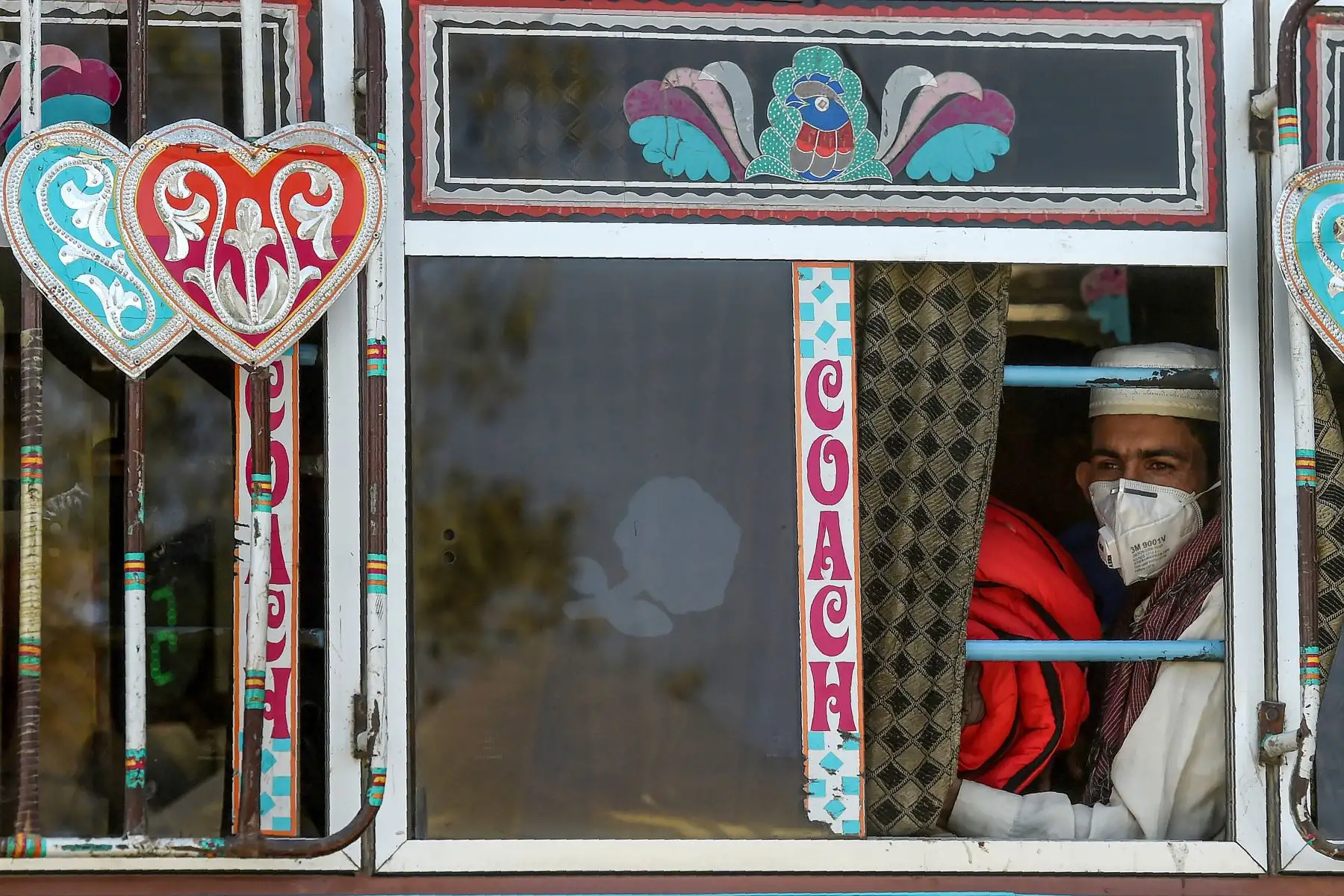 Un pasajero con una máscara facial como medida de prevención contra el coronavirus COVID-19 se sienta en un autobús en Karachi. Foto: AFP