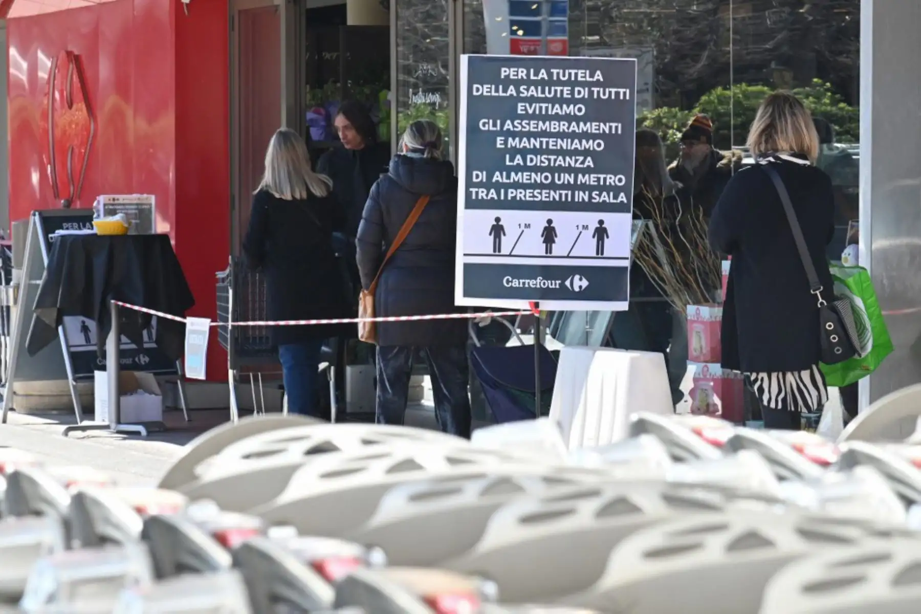 Los residentes esperan en la fila junto a un letrero que dice "Mantener una distancia de un metro" frente al supermercado en el distrito Portuense de Roma. Foto: AFP