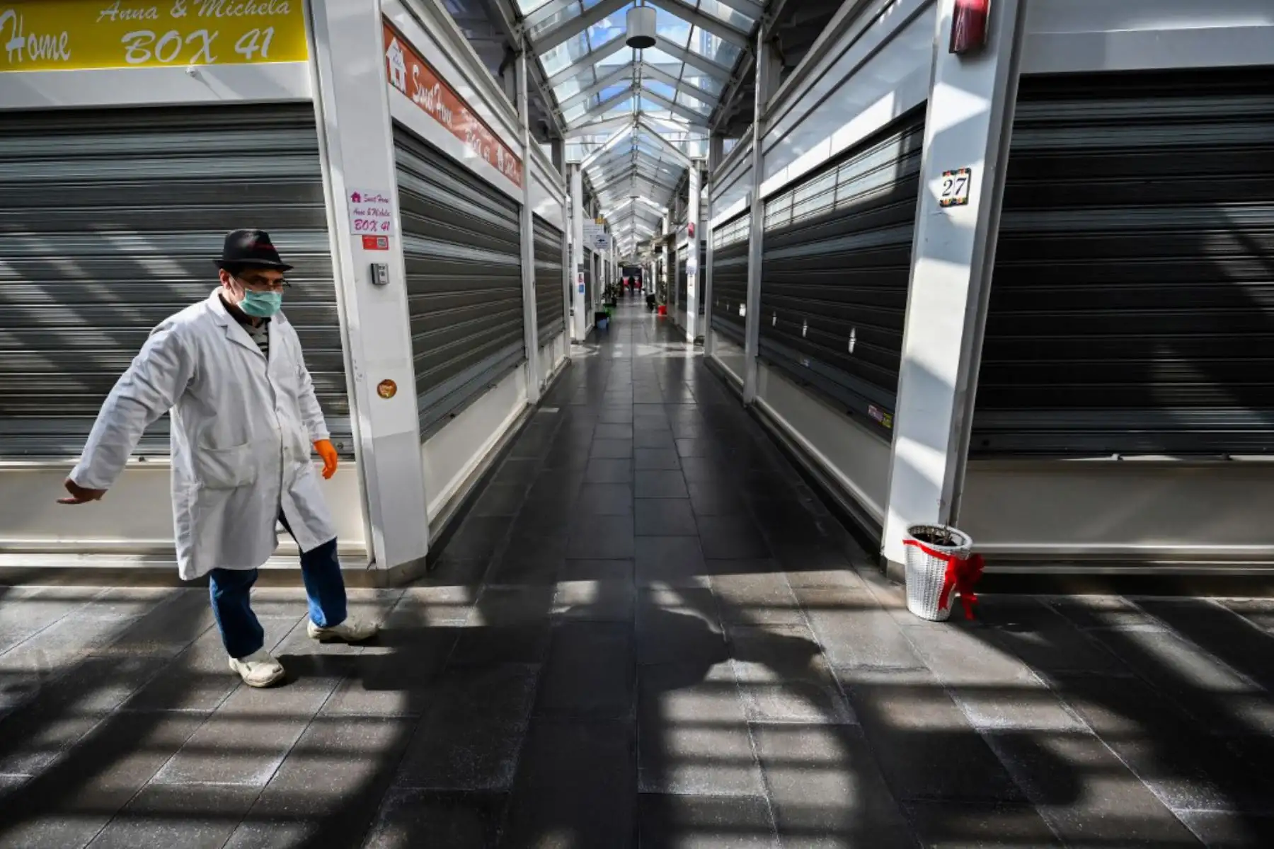 Un trabajador del mercado con una máscara protectora pasa por puestos cerrados en la sección de productos no alimenticios de un mercado en Roma. Foto. AFP