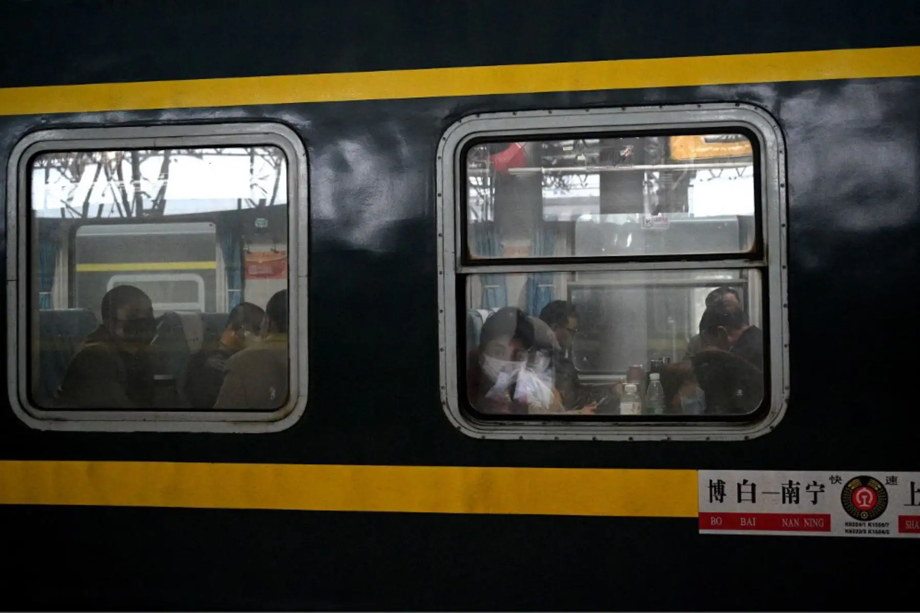 Pasajeros con máscaras faciales se sientan dentro de un tren en la estación de Nanjing en China. Foto: AFP
