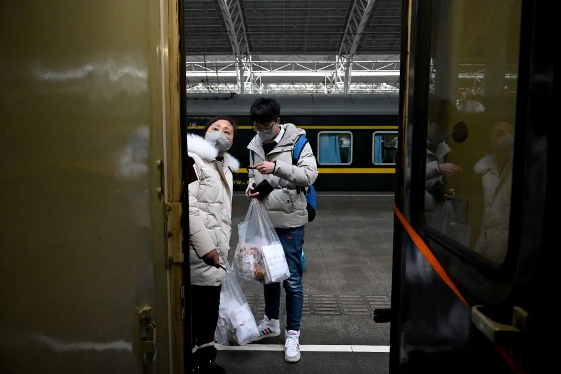 Pasajeros con máscaras faciales se preparan para abordar un tren en la estación de trenes de Nanjing en China. Foto: AFP