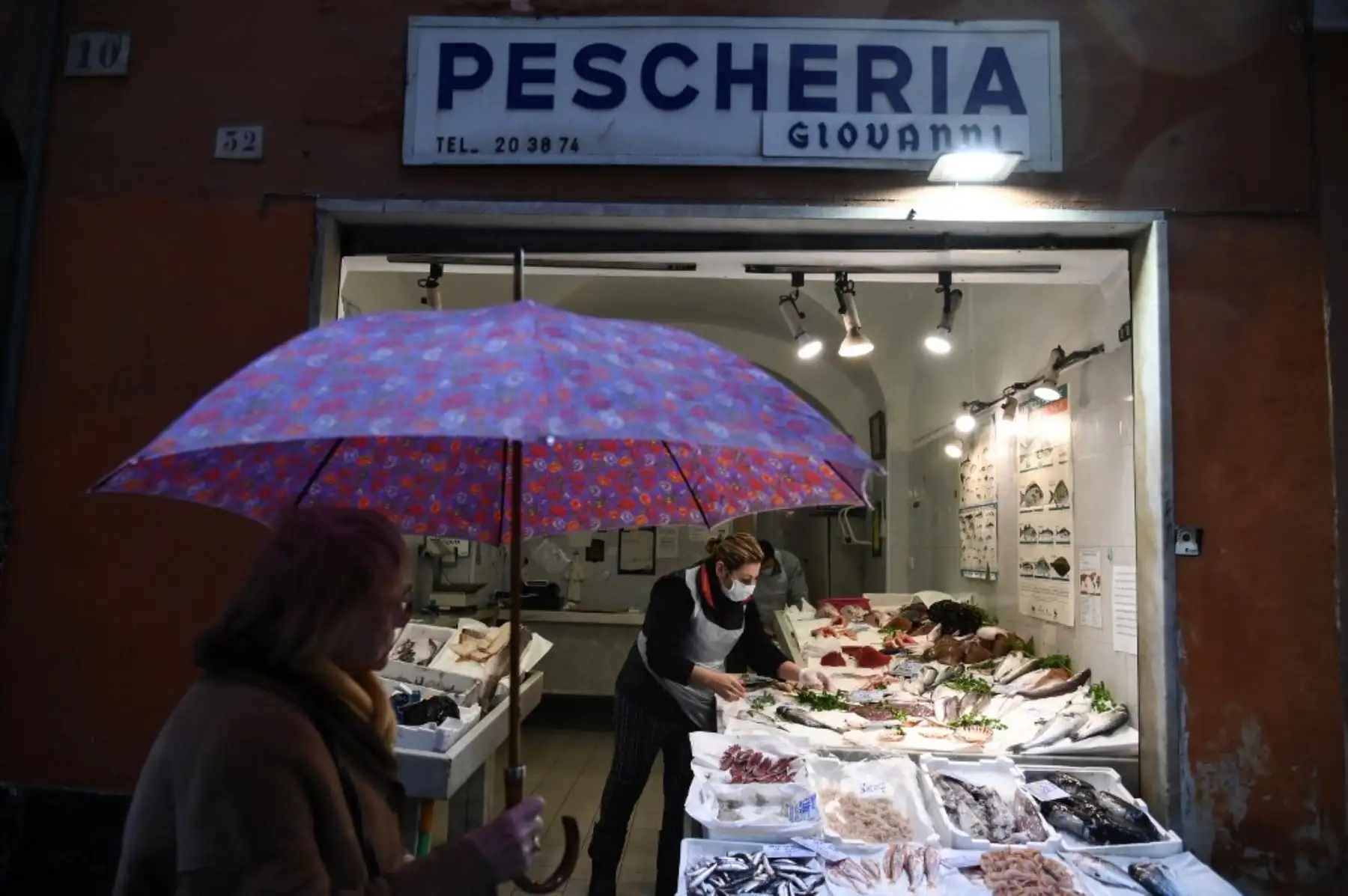 Comerciantes de Génova despechan totalmente protegidos. Foto: AFP