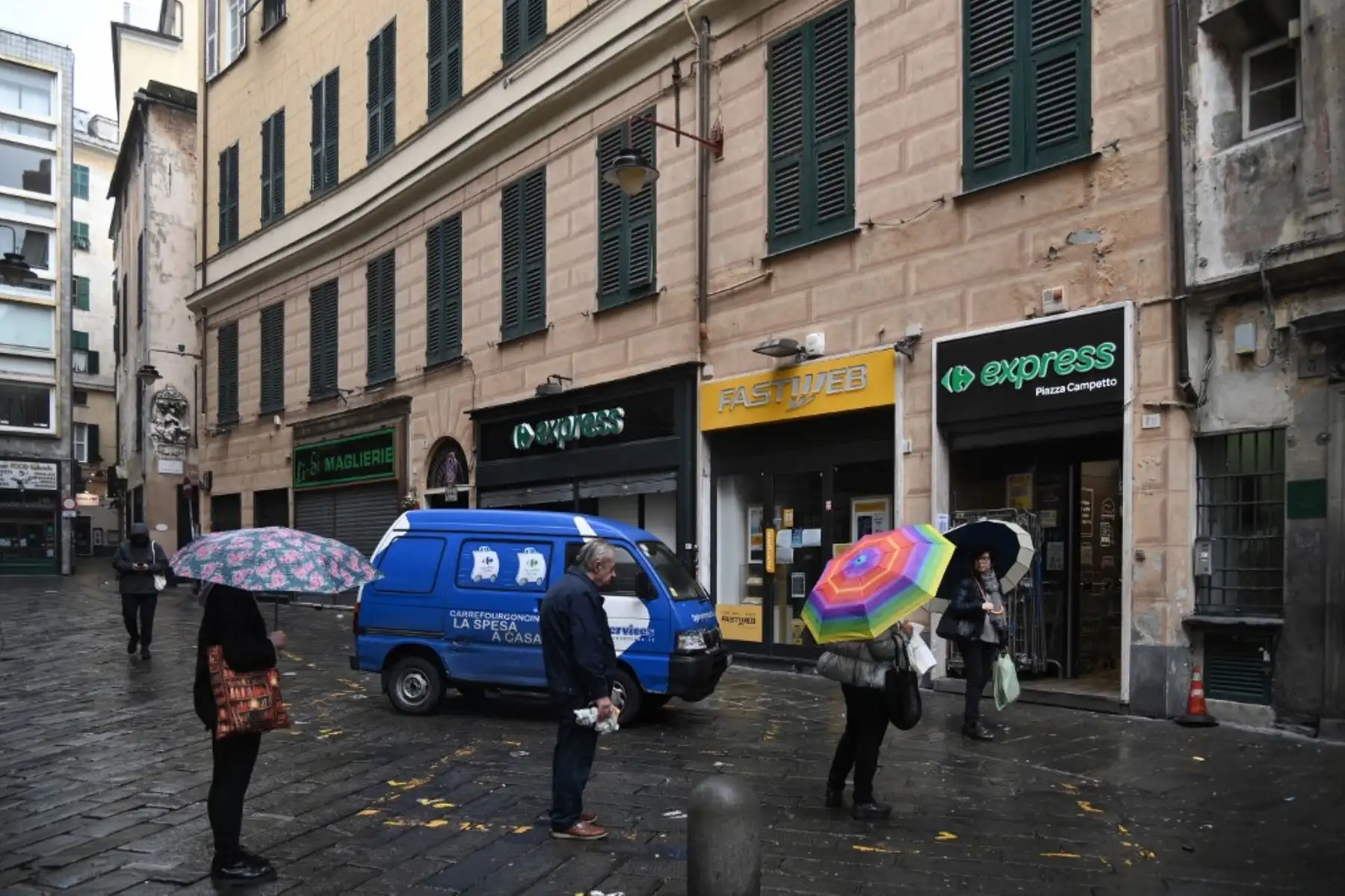 Personas mantiene una distancia de un metro mientras hacen fila para ingresar a un supermercado en la ciudad vieja de Génova. Foto: AFP