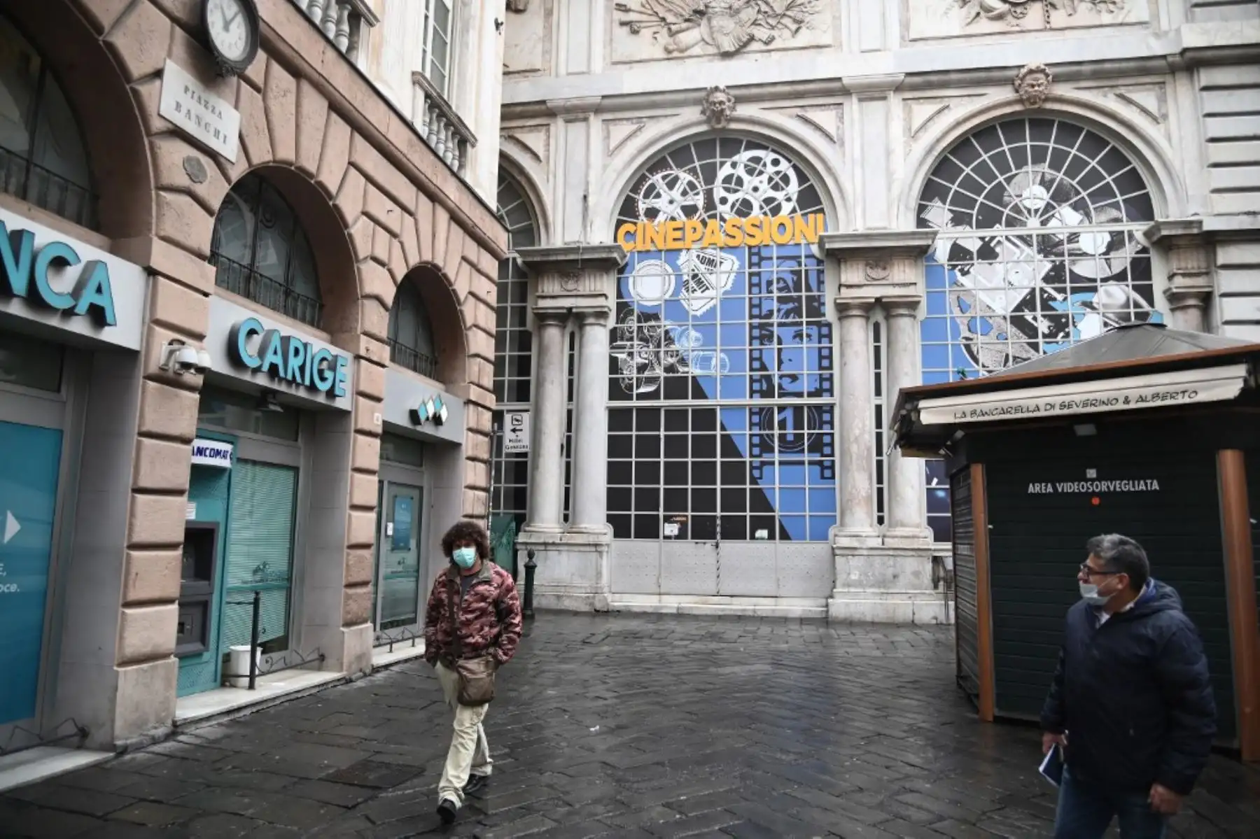 Personas caminan por una zona desierta junto al edificio Loggia Mercanzia del siglo XVI, en Génova. Foto: AFP
