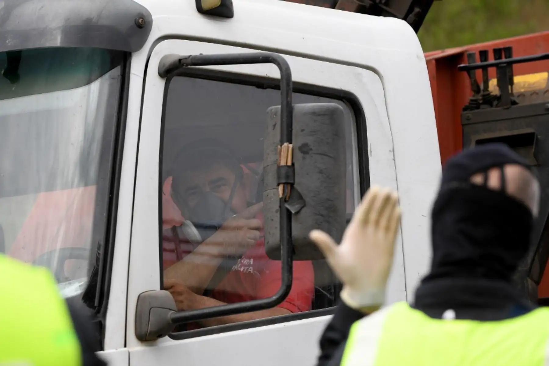Un camionero con una máscara protectora recibe instrucciones de un miembro de la policía regional catalana. Foto: AFP