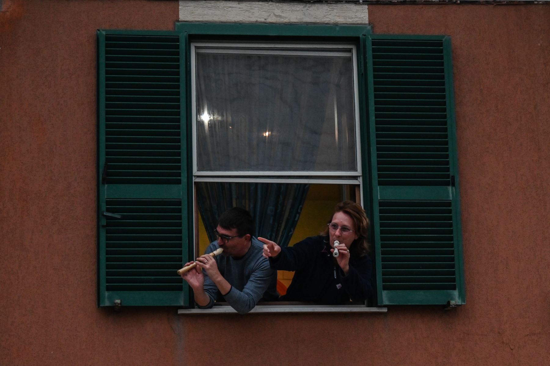 La gente toca el himno nacional italiano con instrumentos musicales desde la ventana de su casa durante un flash mob llamado "¡Mira desde la ventana, Roma mía!" Destinado a animar el silencio de la ciudad durante el nuevo encierro de coronavirus, en Roma.
Foto: AFP