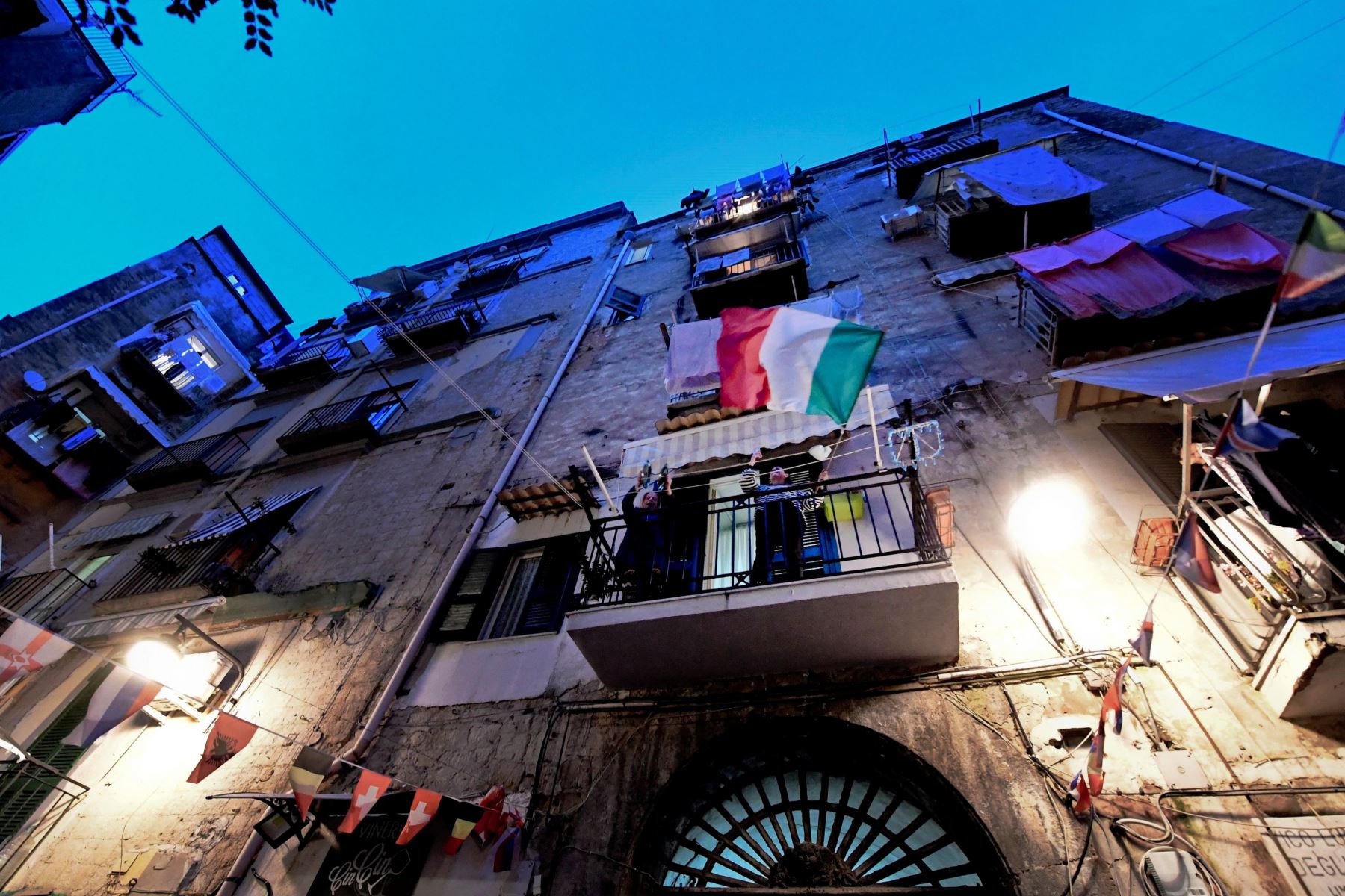 Las personas en los balcones del Quartieri Spagnoli cantan juntas y exhiben la bandera italiana para animarse, ya que están encerradas en Nápoles, Italia.
Foto: EFE