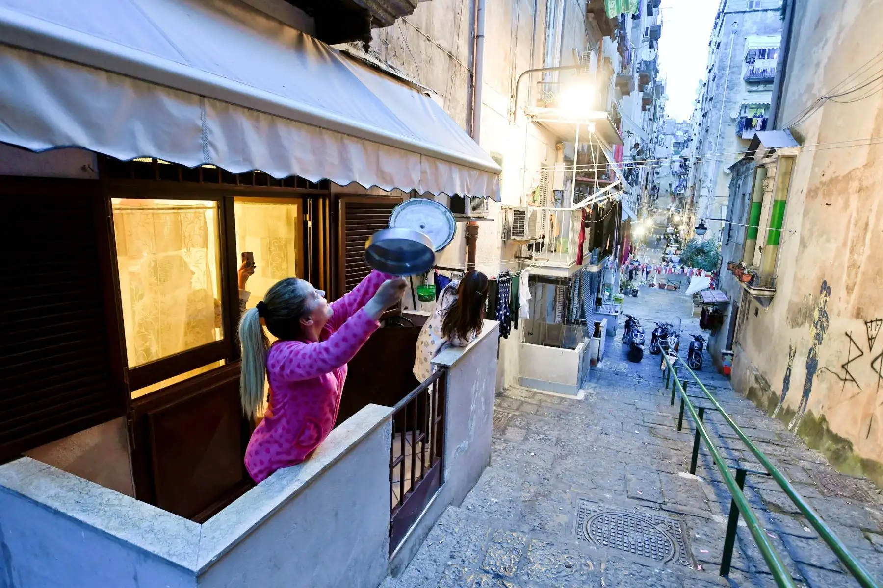 Las personas en los balcones del Quartieri Spagnoli cantan juntas y muestran la bandera italiana para animarse, ya que están encerradas en Nápoles, Italia. Foto: EFE