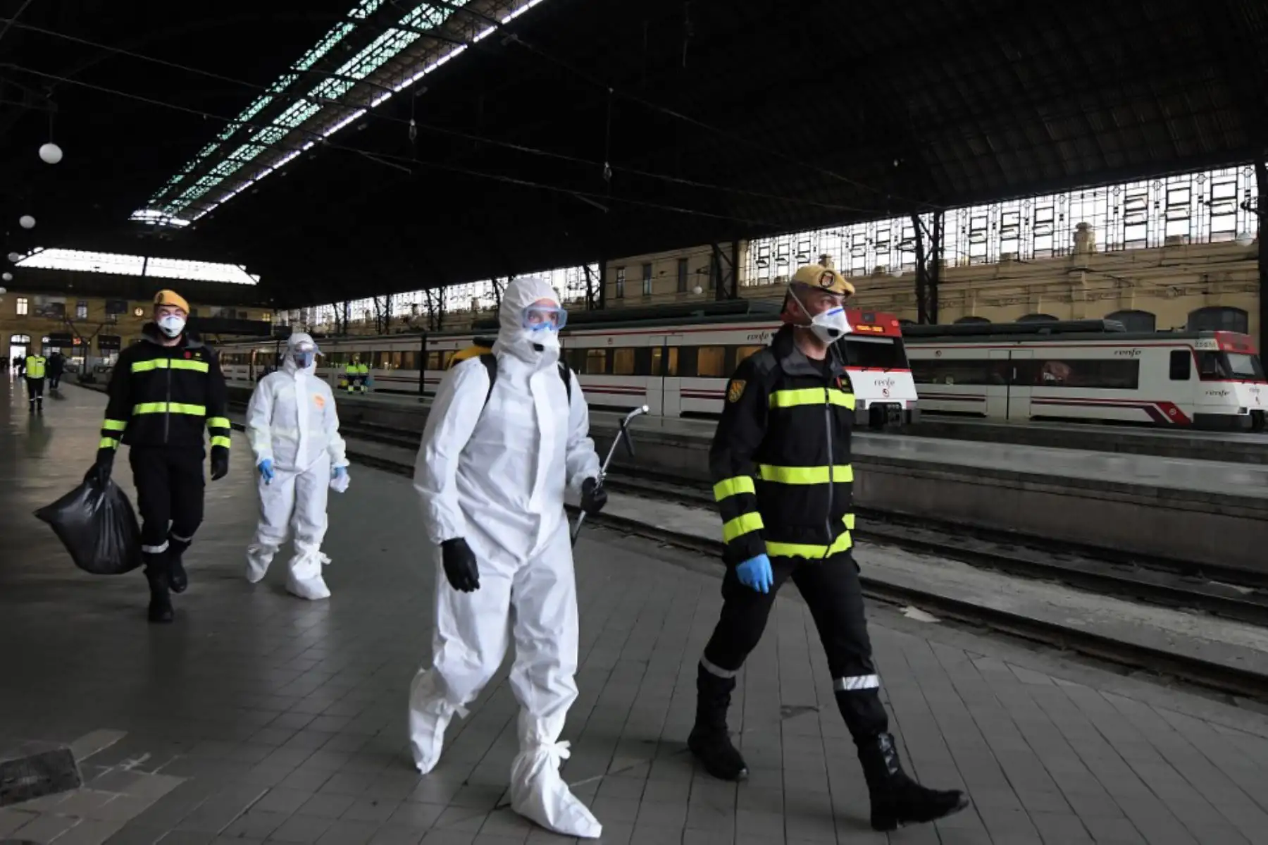 Miembros de la Unidad de Emergencias Militares llevan a cabo una desinfección general en la estación de tren en Valencia. Foto: AFP