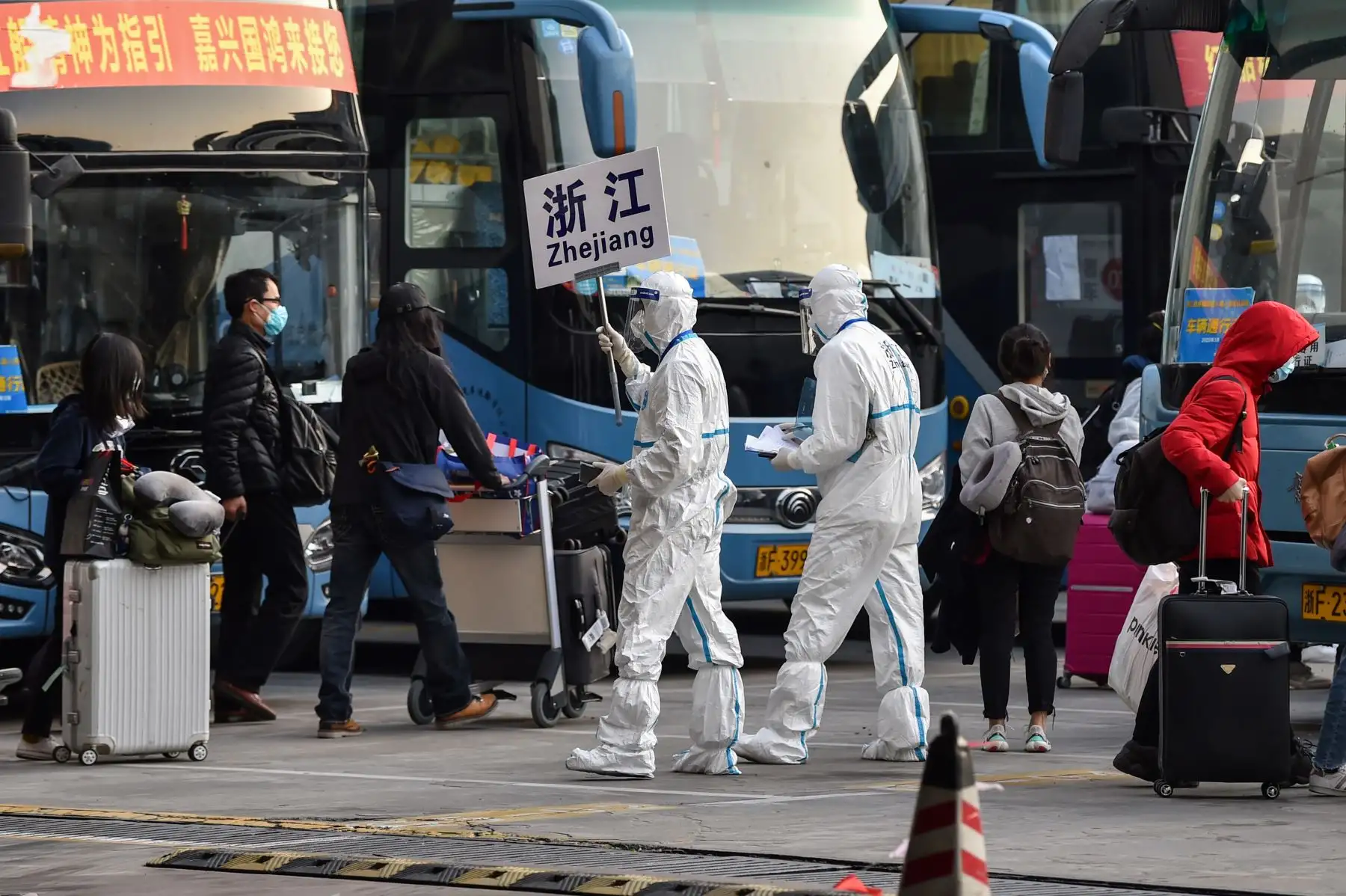 Un trabajador que usa equipo de protección, en medio de preocupaciones por el coronavirus COVID-19, acompaña a los pasajeros a un autobús que los llevará a su ciudad en la provincia de Zhejiang, después de llegar al Aeropuerto Internacional Pudong de Shanghai en Shanghai el 18 de marzo de 2020. Foto: AFP