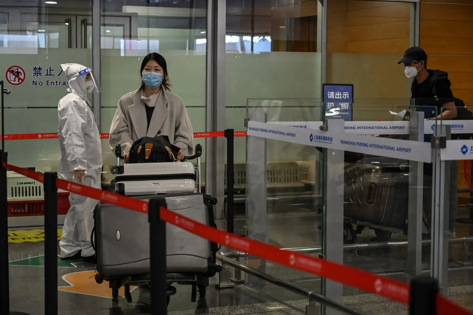 El personal de seguridad del aeropuerto verifica que los pasajeros usen máscaras faciales, en medio de preocupaciones por el coronavirus COVID-19, a su llegada al Aeropuerto Internacional Pudong de Shanghai en Shanghai. Foto: AFP