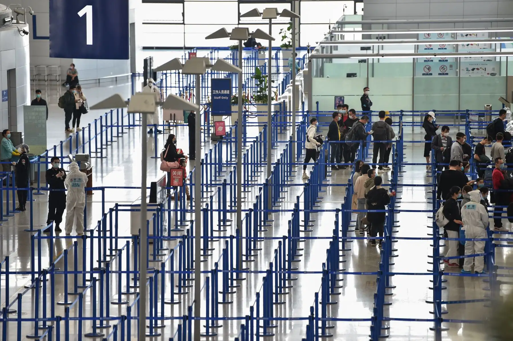 Pasajeros con máscaras faciales, en medio de preocupaciones por el coronavirus COVID-19, hacen cola en el área del mostrador en el Aeropuerto Internacional Pudong de Shanghai en Shanghai, China. Foto: AFP